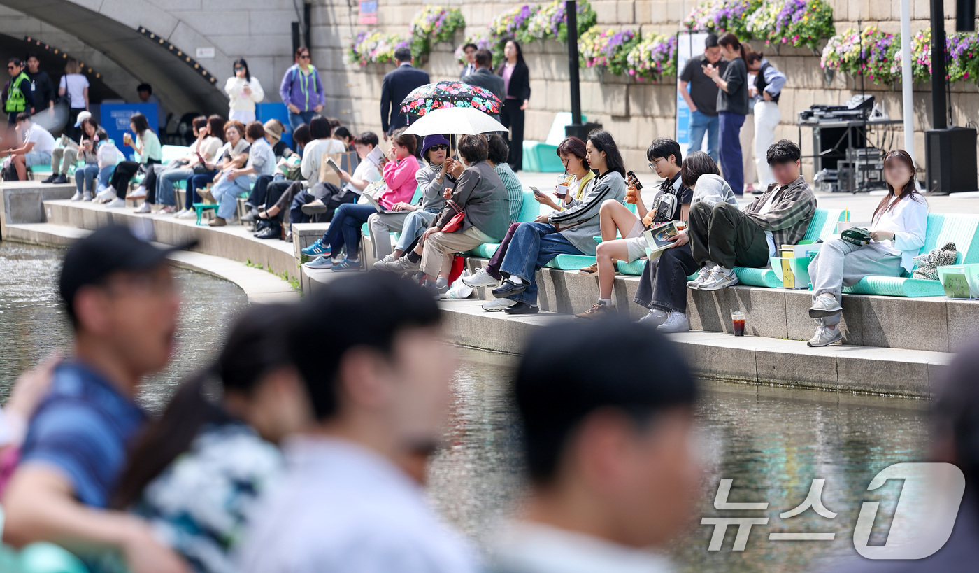 (서울=뉴스1) 김성진 기자 = 낮 최고기온이 25도를 기록하는 등 초여름 날씨를 보인 23일 오후 서울 중구 청계천을 찾은 시민들이 독서를 하고 있다.  2025.4.23/뉴스1 …