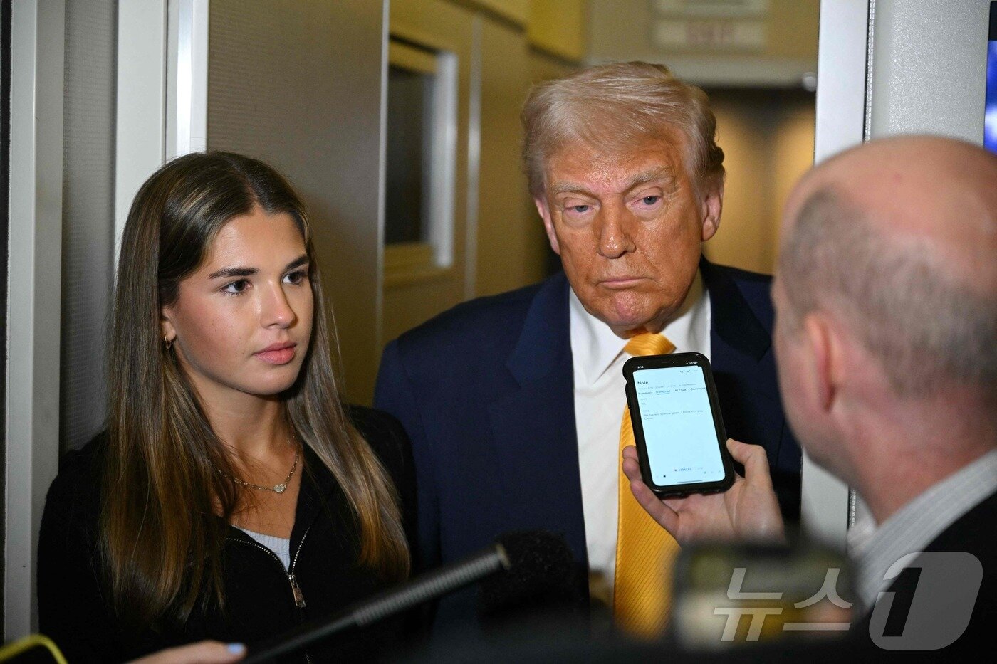 본문 이미지 - 도널드 트럼프 미국 대통령이 13일&#40;현지시간&#41; 마이애미에서 팜비치로 향하는 에어포스원에서 기자의 질문에 답하는 동안 손녀 카이 트럼프가 그 옆에서 듣고 있다. 2025.04.13.  ⓒ AFP=뉴스1
