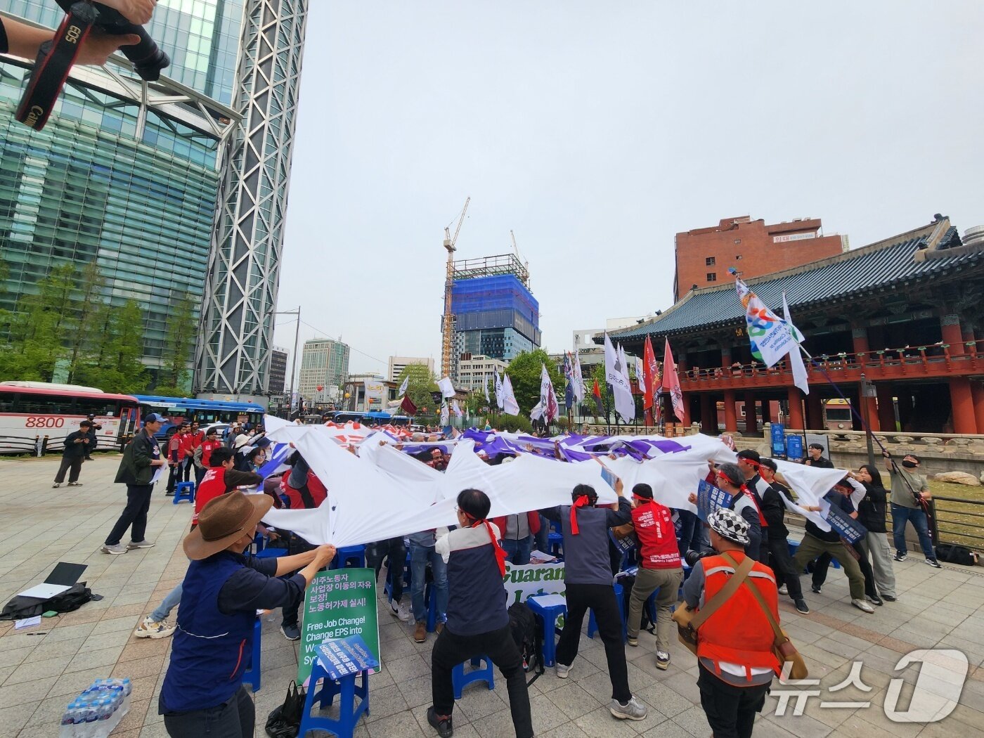 본문 이미지 - 27일 서울시 종로구 보신각 앞에서 이주노동자들이 차별과 노동권 제한에 항의하는 뜻으로 현수막을 찢는 퍼포먼스를 선보이고 있다. 2025.04.27/ⓒ 뉴스1 권진영 기자