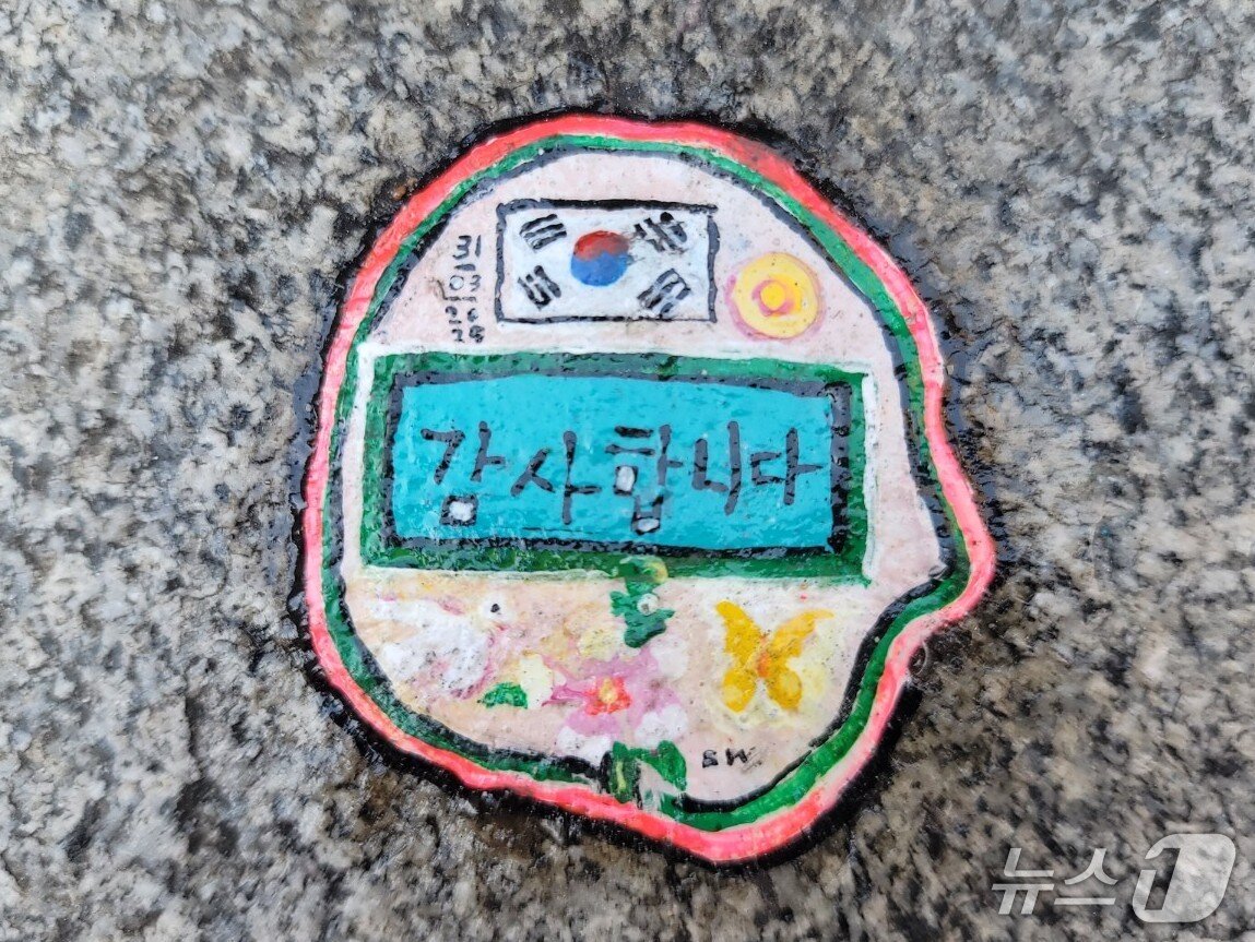 본문 이미지 - 벤 윌슨이 세인트폴 성당에서 밀레니엄 브리지로 이어지는 길목의 한쪽 계단에 만든 위의 껌딱지 작품 안에는 ‘감사합니다’라는 한글과 태극기가 있다. 윌슨은 우측 상단에 한국이 지금의 모든 어려움을 이겨내길 바라는 마음을 담아 해를 그려 넣었다. 아래에는 평화를 상징하는 흰색 비둘기와 무궁화, 위안부 피해자들을 상징하는 노랑나비가 차례로 새겨졌다. @조아현