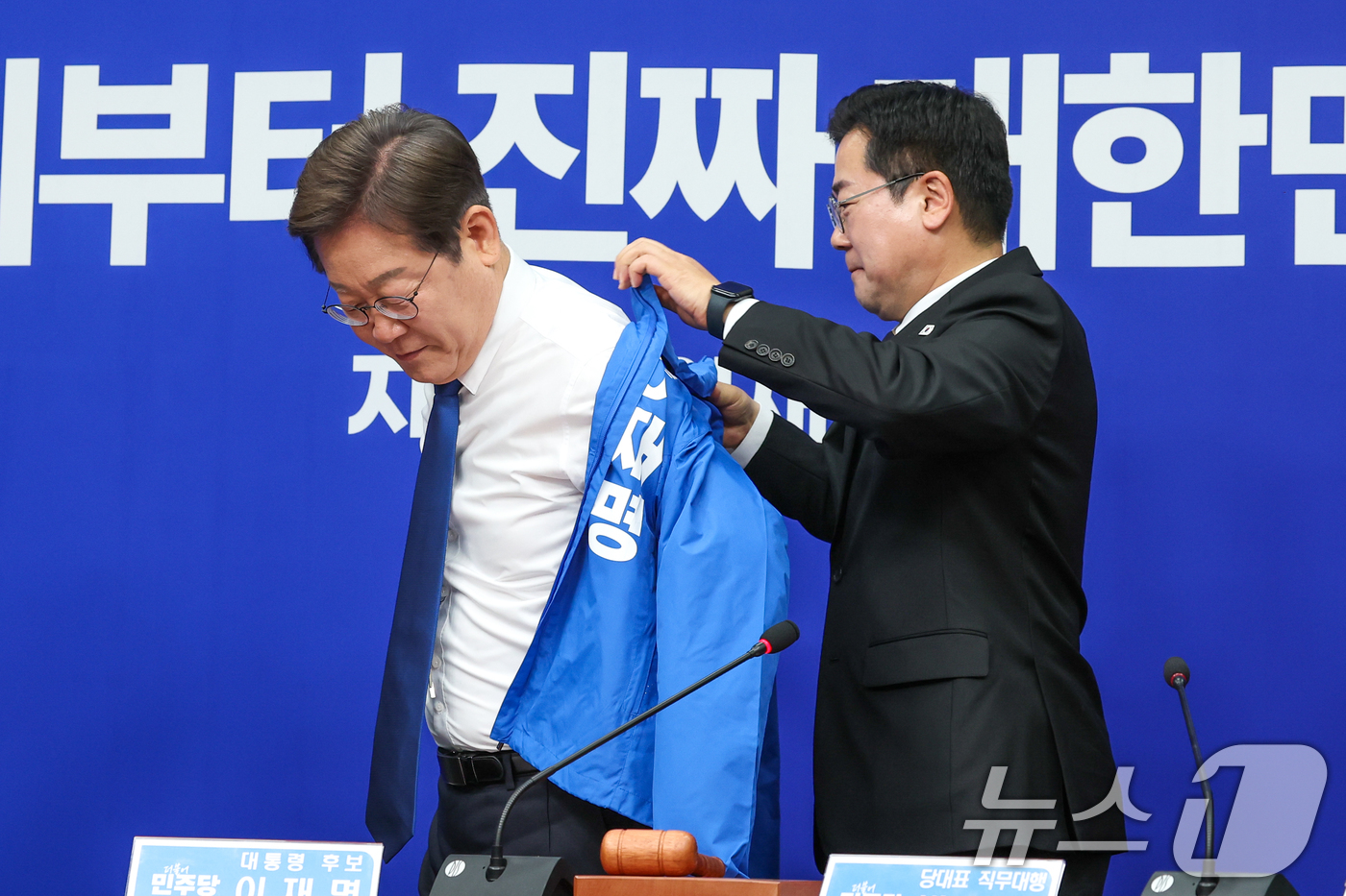 (서울=뉴스1) 안은나 기자 = 박찬대 더불어민주당 대표 직무대행 겸 원내대표가 28일 서울 여의도 국회에서 열린 최고위원회의에서 이재명 대선 후보에게 선거복을 입혀주고 있다. 2 …