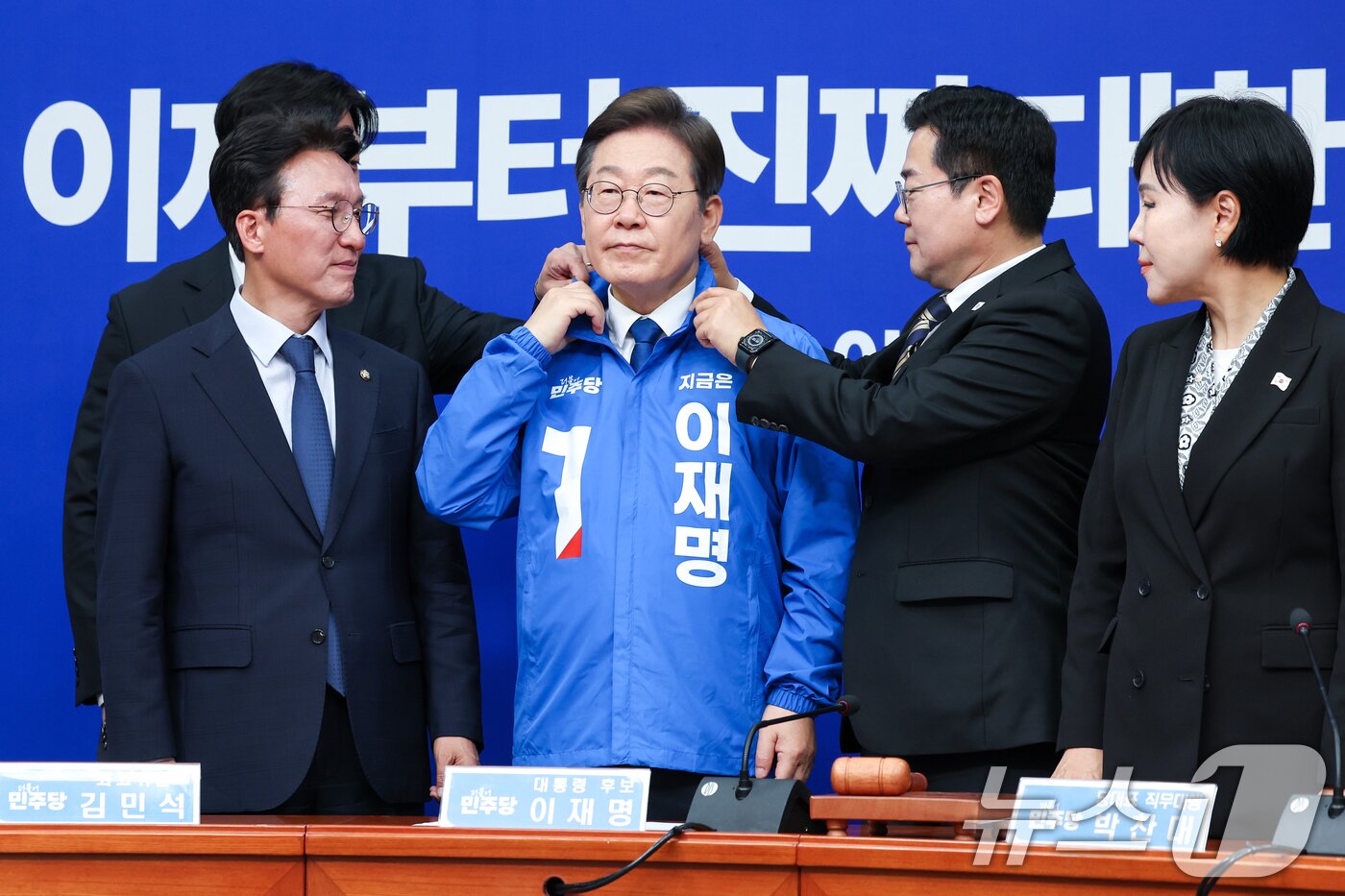 본문 이미지 - 박찬대 더불어민주당 대표 직무대행 겸 원내대표가 28일 서울 여의도 국회에서 열린 최고위원회의에서 이재명 대선 후보에게 선거복을 입혀준 뒤 옷깃을 정리하고 있다. 왼쪽부터 한준호, 김민석 최고위원, 이 후보, 박 직무대행, 전현희 최고위원. 2025.4.28/뉴스1 ⓒ News1 안은나 기자