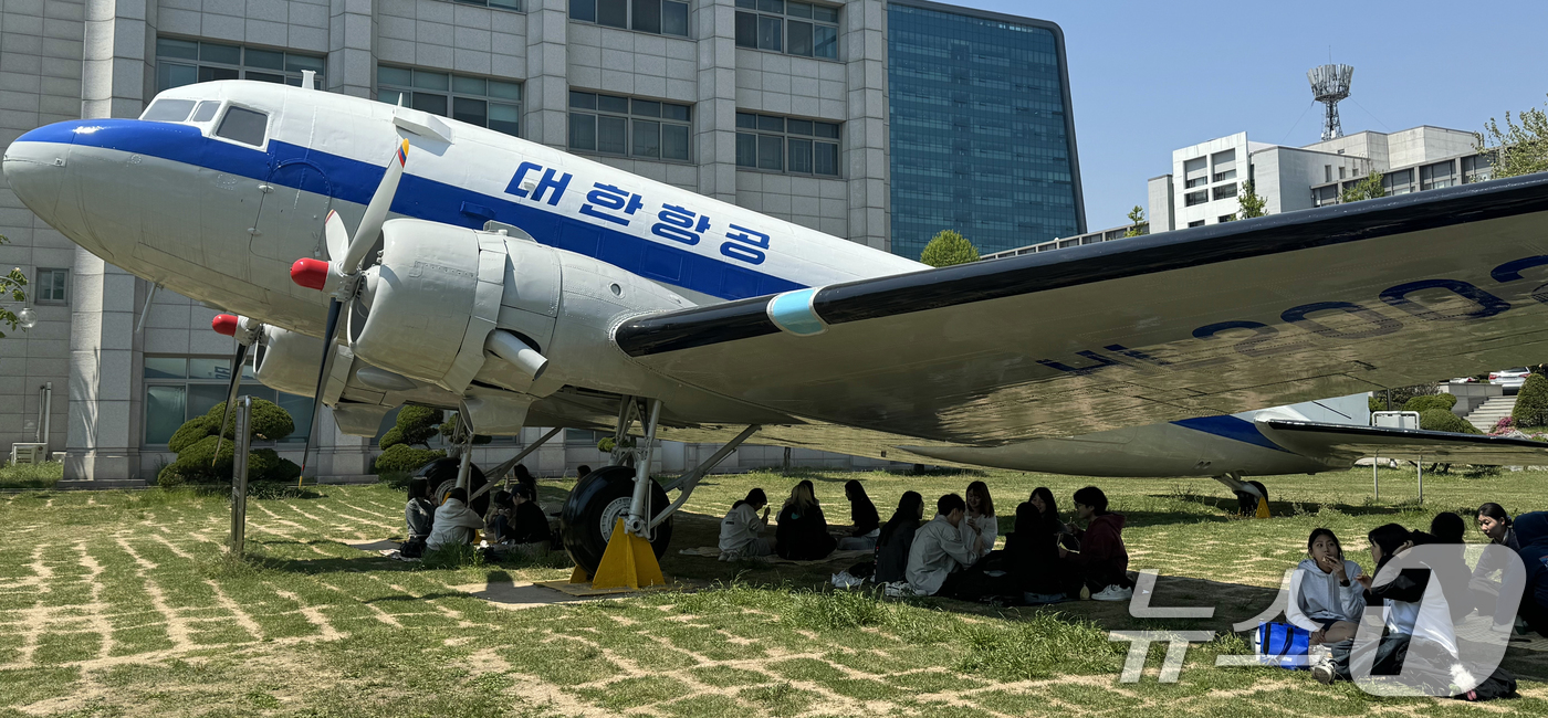 (인천=뉴스1) 김명섭 기자 = 29일 인천광역시 미추홀구 인하대학교에서 학생들이 따가운 봄 햇살을 피해 비행기 그늘 아래에서 피크닉을 즐기고 있다.이 항공기는 1954년 도입된 …