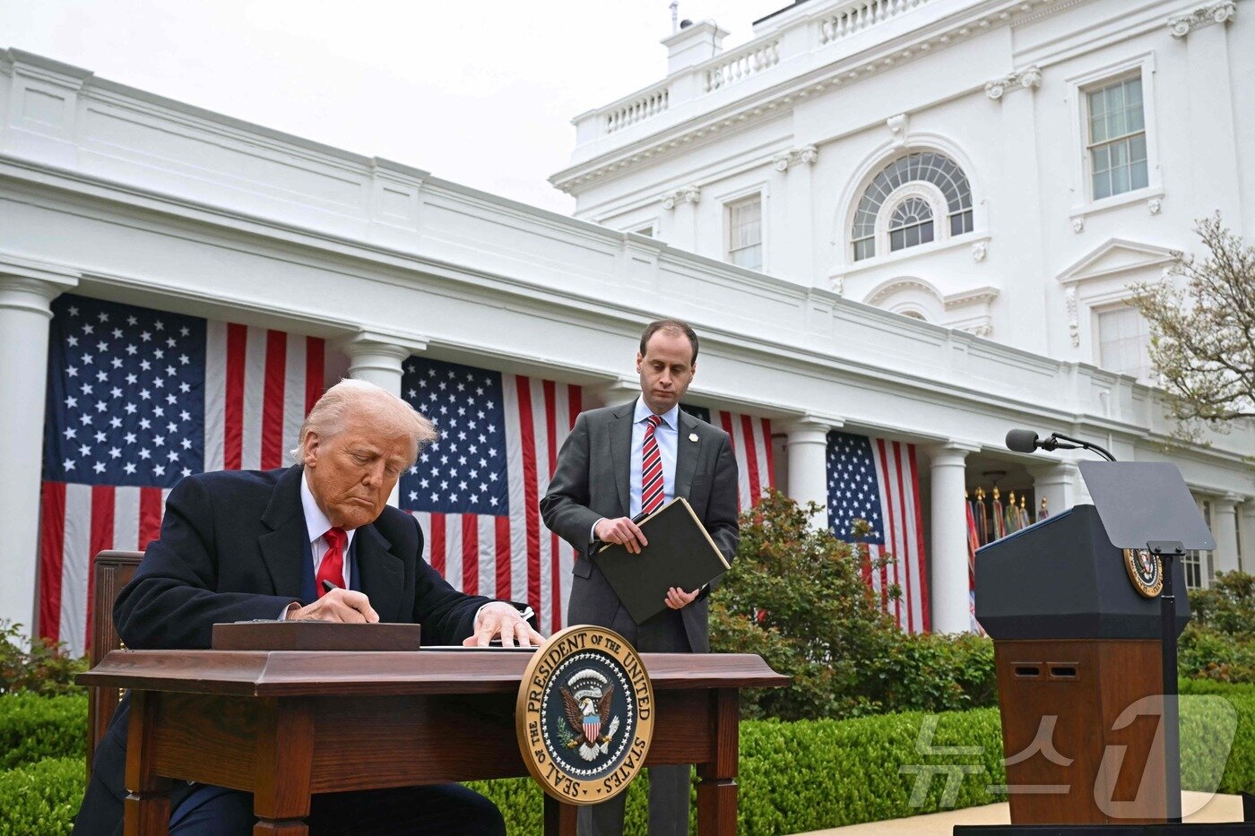본문 이미지 - 도널드 트럼프 미국 대통령이 2일(현지시간) 미국 워싱턴 D.C. 백악관 로즈가든에서 상호 관세 부과 방침을 전격 발표 후 행정명령서에 서명을 하고 있다. ⓒ AFP=뉴스1