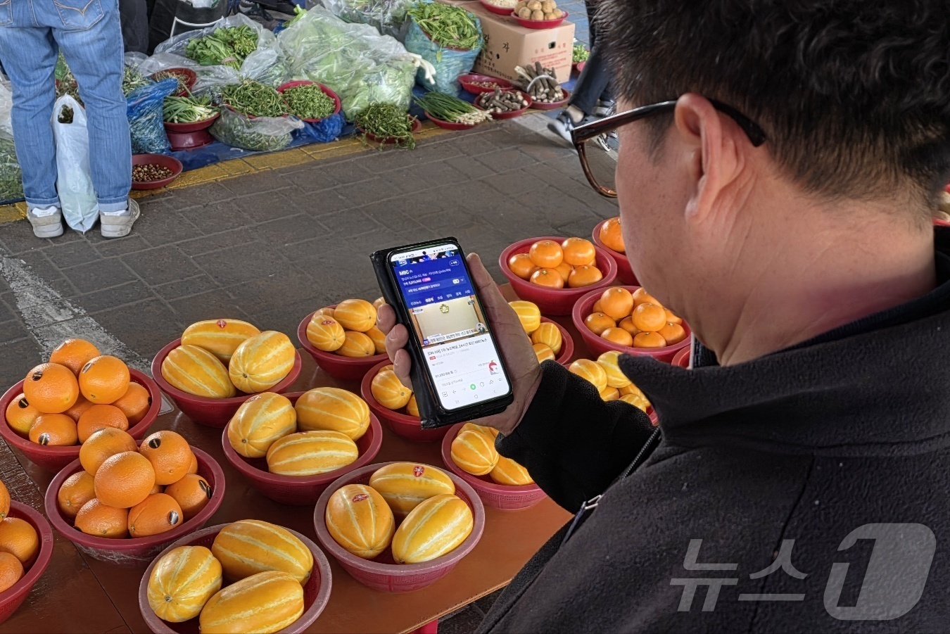 (아산=뉴스1) 이시우 기자 = 4일 충남 아산 온양온천역 풍물 오일장에서 한 상인이 휴대전화로 윤석열 대통령에 대한 탄핵 심판 선고 생중계를 지켜보고 있다.  2025.4.4/뉴 …