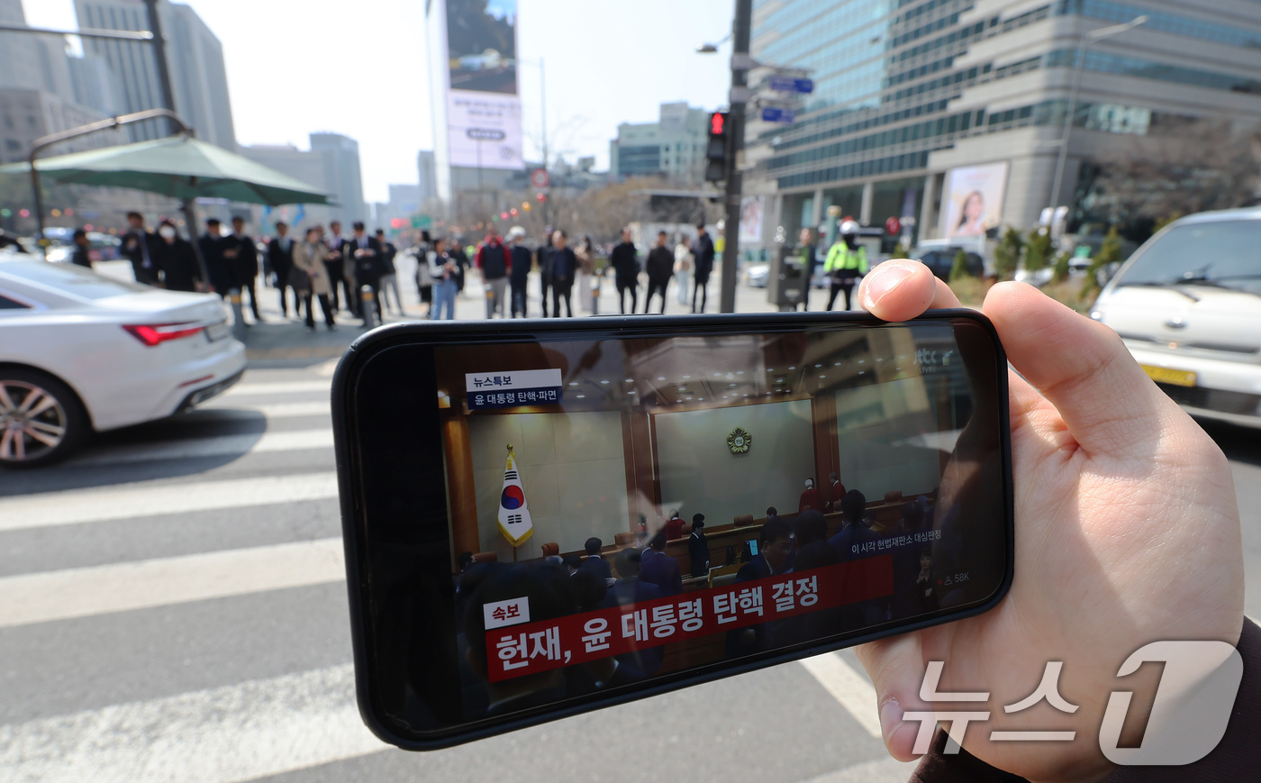 (서울=뉴스1) 장수영 기자 = 윤석열 대통령 탄핵심판 선고일인 4일 서울 중구 세종대로사거리에서 시민이 대통령 파면 인용 생중계를 시청하고 있다.이날 헌법재판소는 재판관 전원 일 …