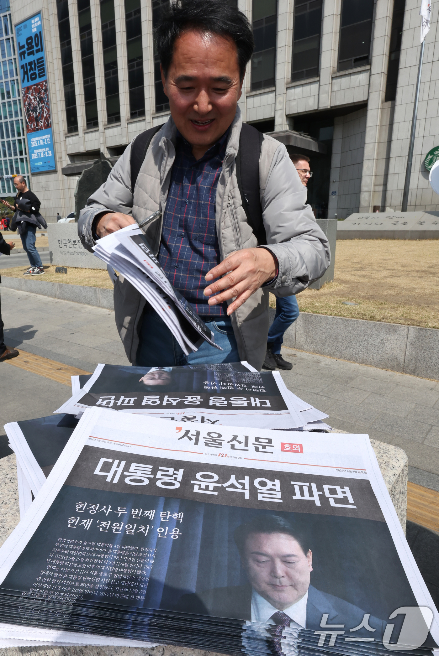 (서울=뉴스1) 장수영 기자 = 헌법재판소가 윤석열 전 대통령에 대한 탄핵을 인용한 4일 오후 서울 중구 시청역 앞에서 시민이 서울신문이 발행한 호외를 가져가고 있다.  2025. …