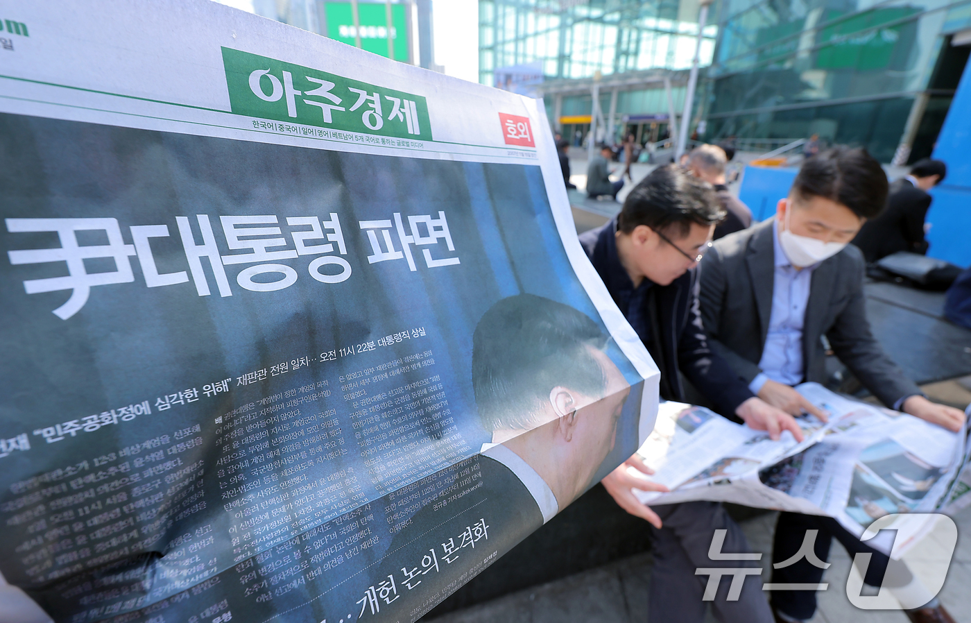 (서울=뉴스1) 박정호 기자 = 윤석열 대통령에 대한 파면이 결정된 4일 오후 서울 용산구 한강대로 서울역에서 시민들이 아주경제의 호외를 읽고 있다.헌법재판소는 이날 오전 11시 …