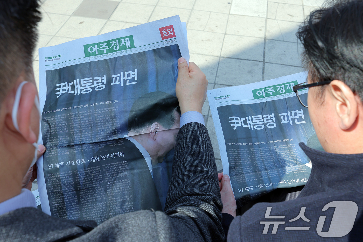 (서울=뉴스1) 박정호 기자 = 윤석열 대통령에 대한 파면이 결정된 4일 오후 서울 용산구 한강대로 서울역에서 시민들이 아주경제의 호외를 읽고 있다.헌법재판소는 이날 오전 11시 …
