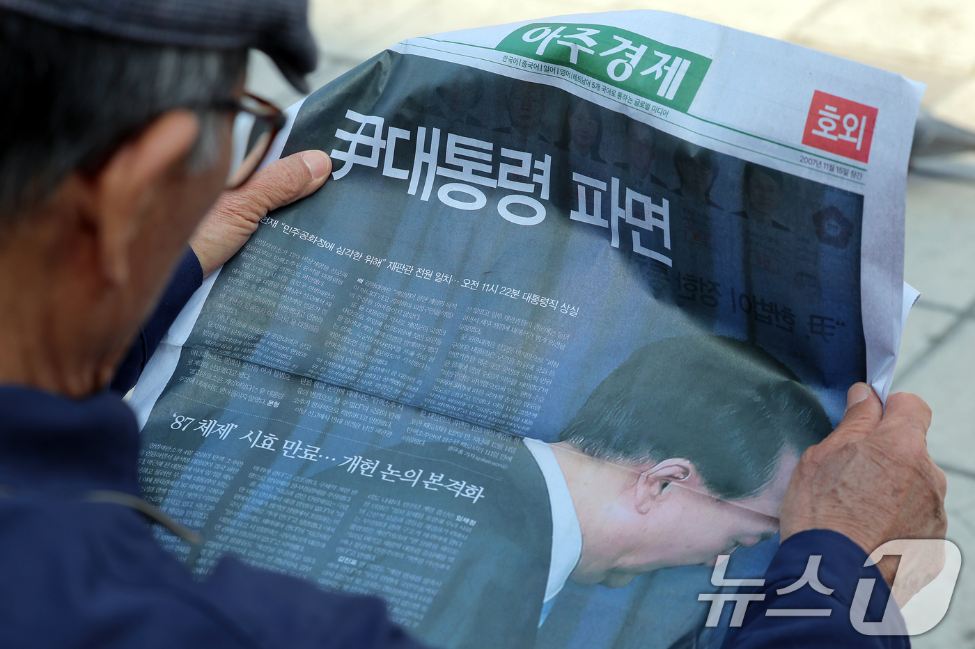 (서울=뉴스1) 박정호 기자 = 윤석열 대통령에 대한 파면이 결정된 4일 오후 서울 용산구 한강대로 서울역에서 시민들이 아주경제의 호외를 읽고 있다.헌법재판소는 이날 오전 11시 …