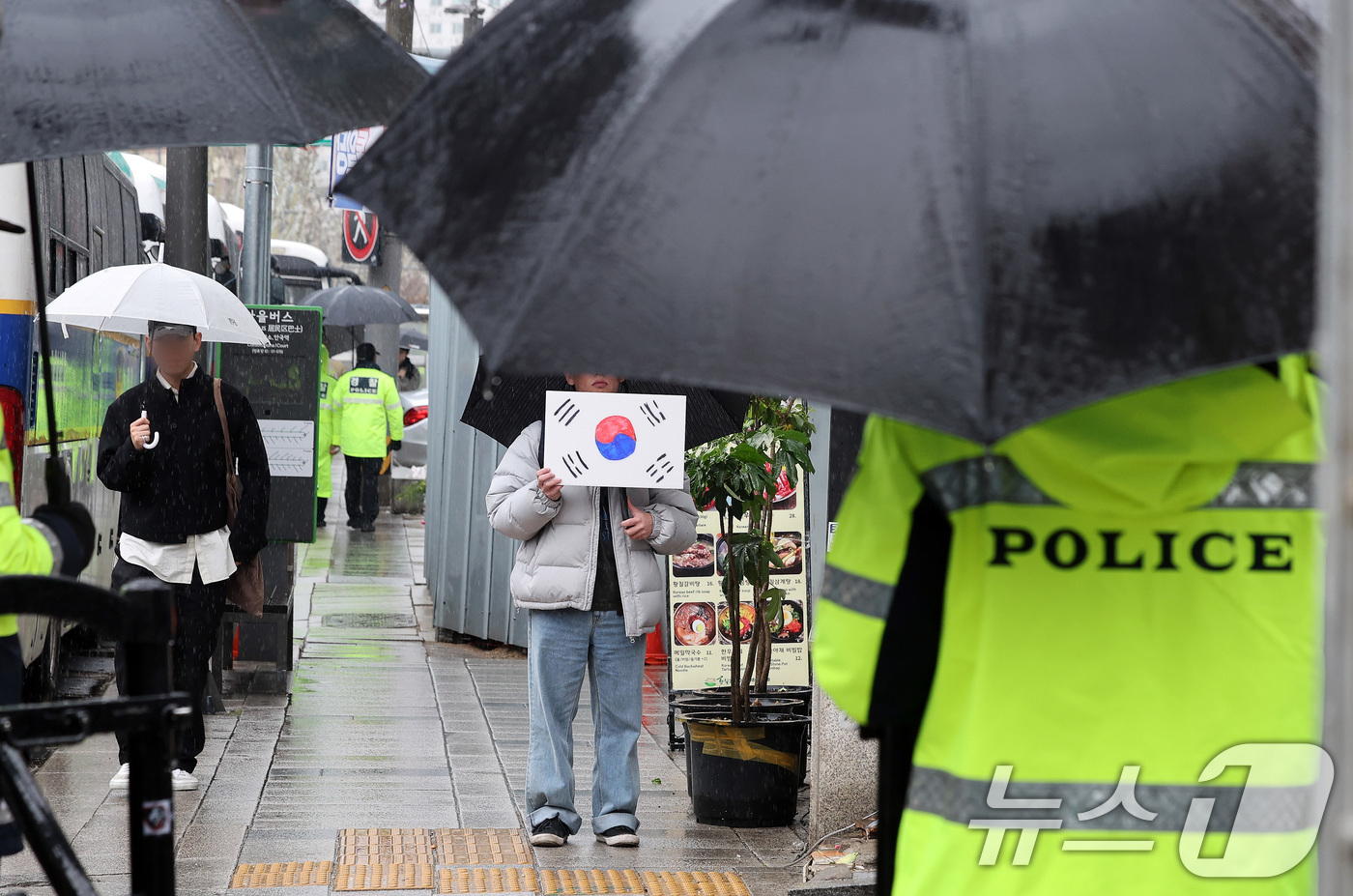 (서울=뉴스1) 이동해 기자 = 헌법재판소의 윤석열 전 대통령에 대한 파면 선고가 하루 지난 5일 서울 종로구 헌법재판소 인근에서 한 시민이 태극기를 든 채 경찰과 대치하고 있다. …