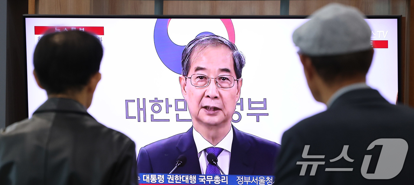 (서울=뉴스1) 박지혜 기자 = 시민들이 1일 오후 서울역 대합실에서 한덕수 대통령 권한대행 국무총리의 대국민담화 발표 생중계 영상을 시청하고 있다.이날 한 대통령 권한대행 국무총 …