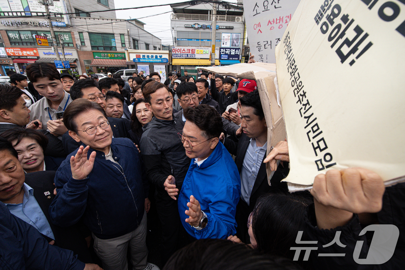 (연천=뉴스1) 이재명 기자 = 이재명 더불어민주당 대통령 후보가 1일 오후 경기도 연천군 전곡시외터미널 인근에서 한 시민이 들고 있는 손피켓 내용을 살펴보고 있다. 2025.5. …