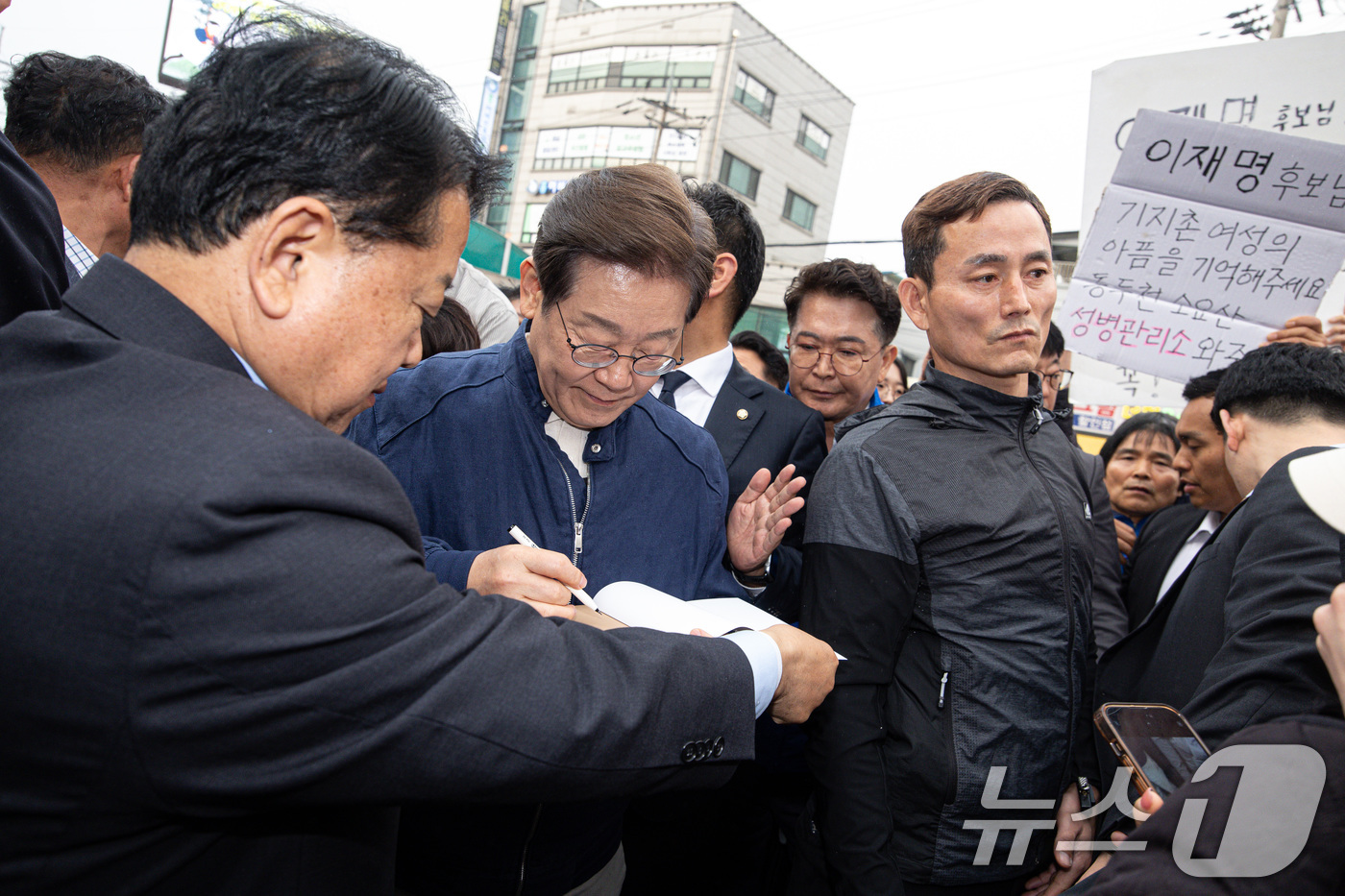 (연천=뉴스1) 이재명 기자 = 이재명 더불어민주당 대통령 후보가 1일 오후 경기도 연천군 전곡시외터미널 인근에서 한 시민 요청으로 책에 서명하고 있다. 2025.5.1/뉴스1