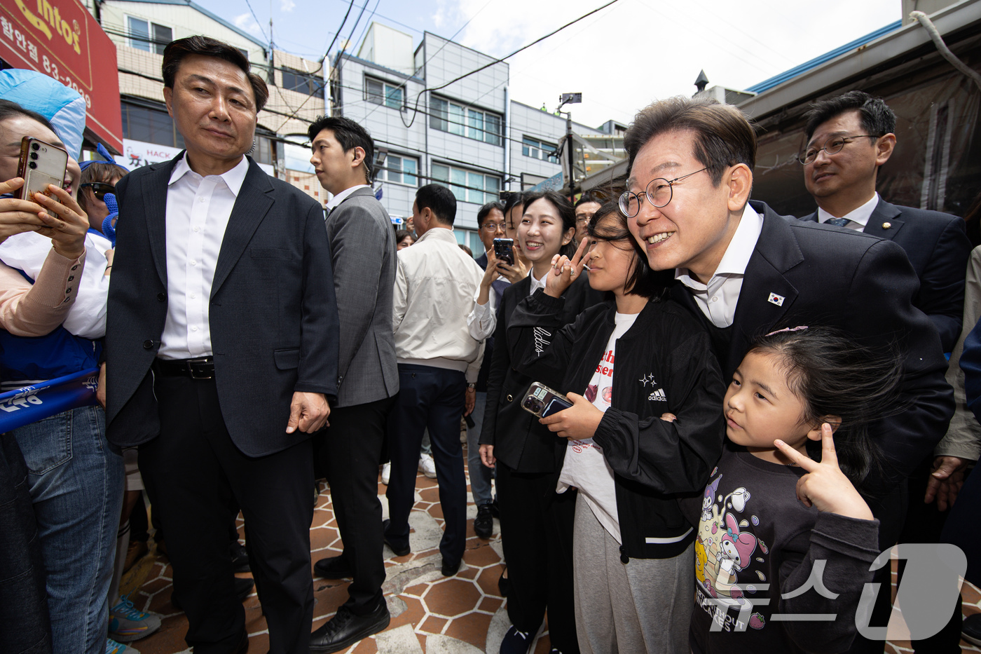 (함안=뉴스1) 이재명 기자 = 경청투어에 나선 이재명 더불어민주당 대통령 후보가 10일 오전 경남 함안군 가야읍 가야시장에서 어린이들과 기념촬영을 하고 있다. 2025.5.10/ …