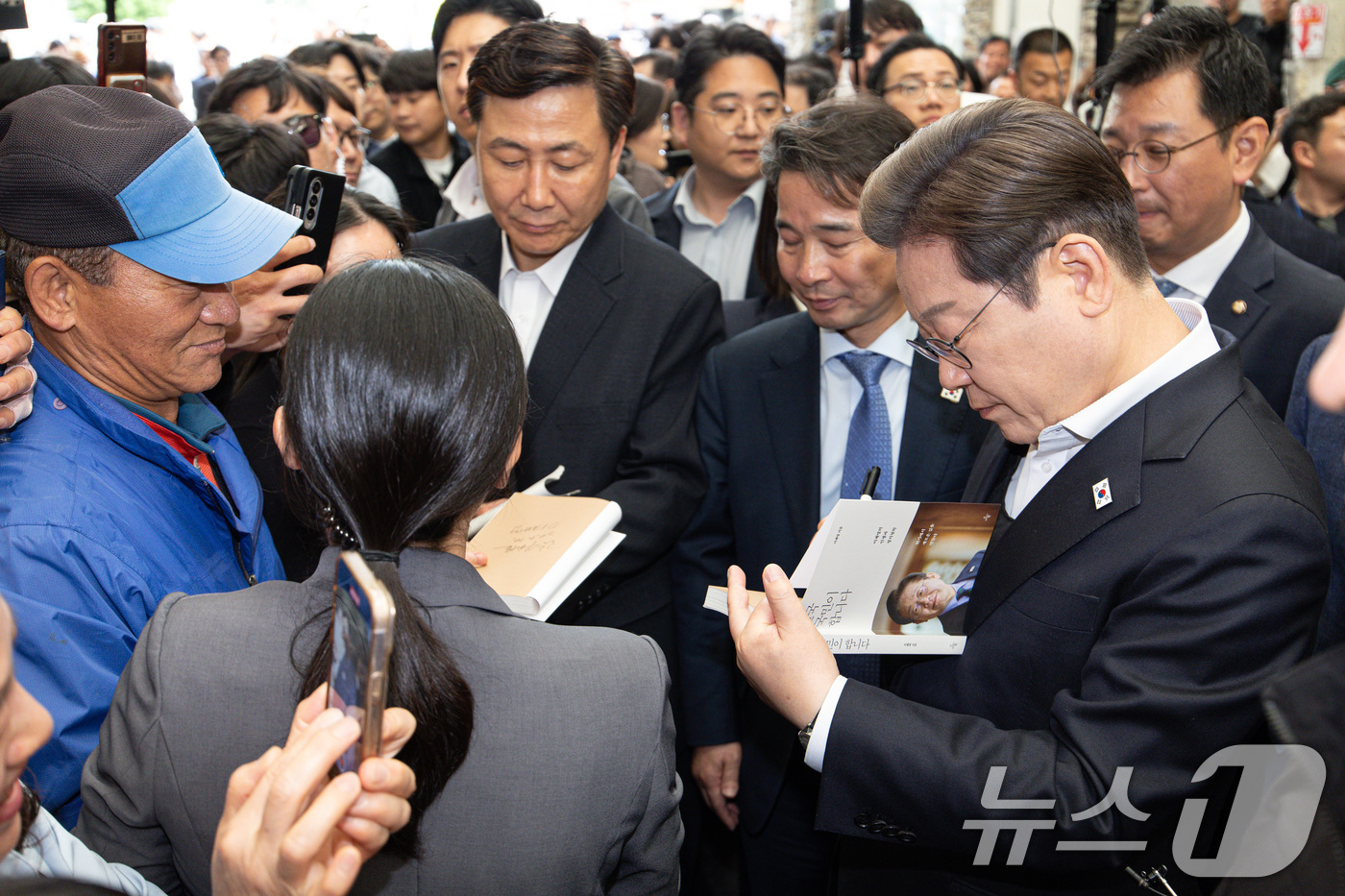 (의령=뉴스1) 이재명 기자 = 경청투어에 나선 이재명 더불어민주당 대통령 후보가 10일 오전 경남 의령군 의령읍 의령전통시장에서 책에 사인하고 있다. 2025.5.10/뉴스1
