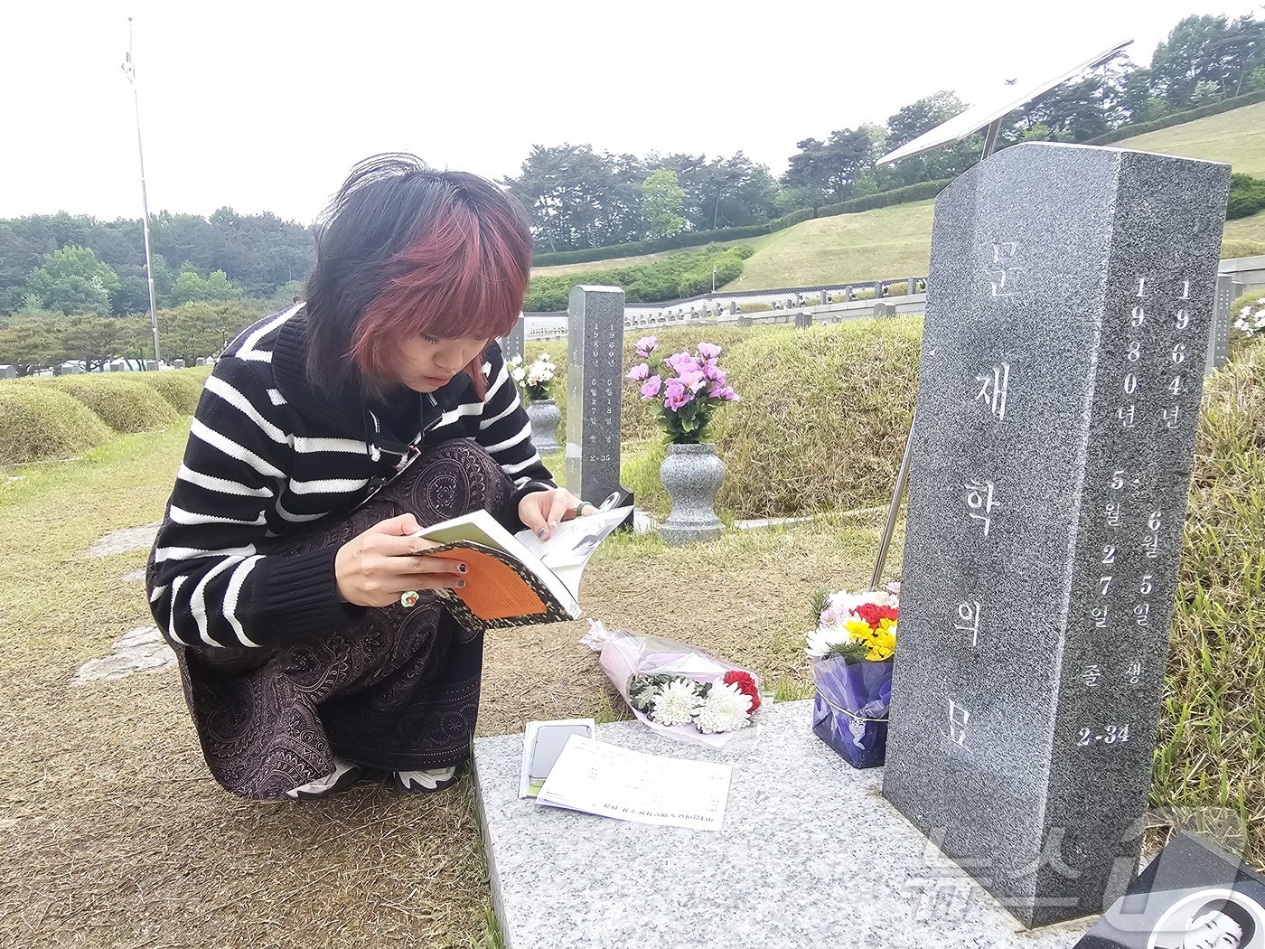 (광주=뉴스1) 서충섭 기자 = 11일 광주 북구 운정동 5·18민주묘역에서 태국 대학생 나띠씨가 소설 ‘소년이 온다’의 실제 모델인 문재학 군 묘소에 놓인 ‘소년이 온다’를 펼쳐 …