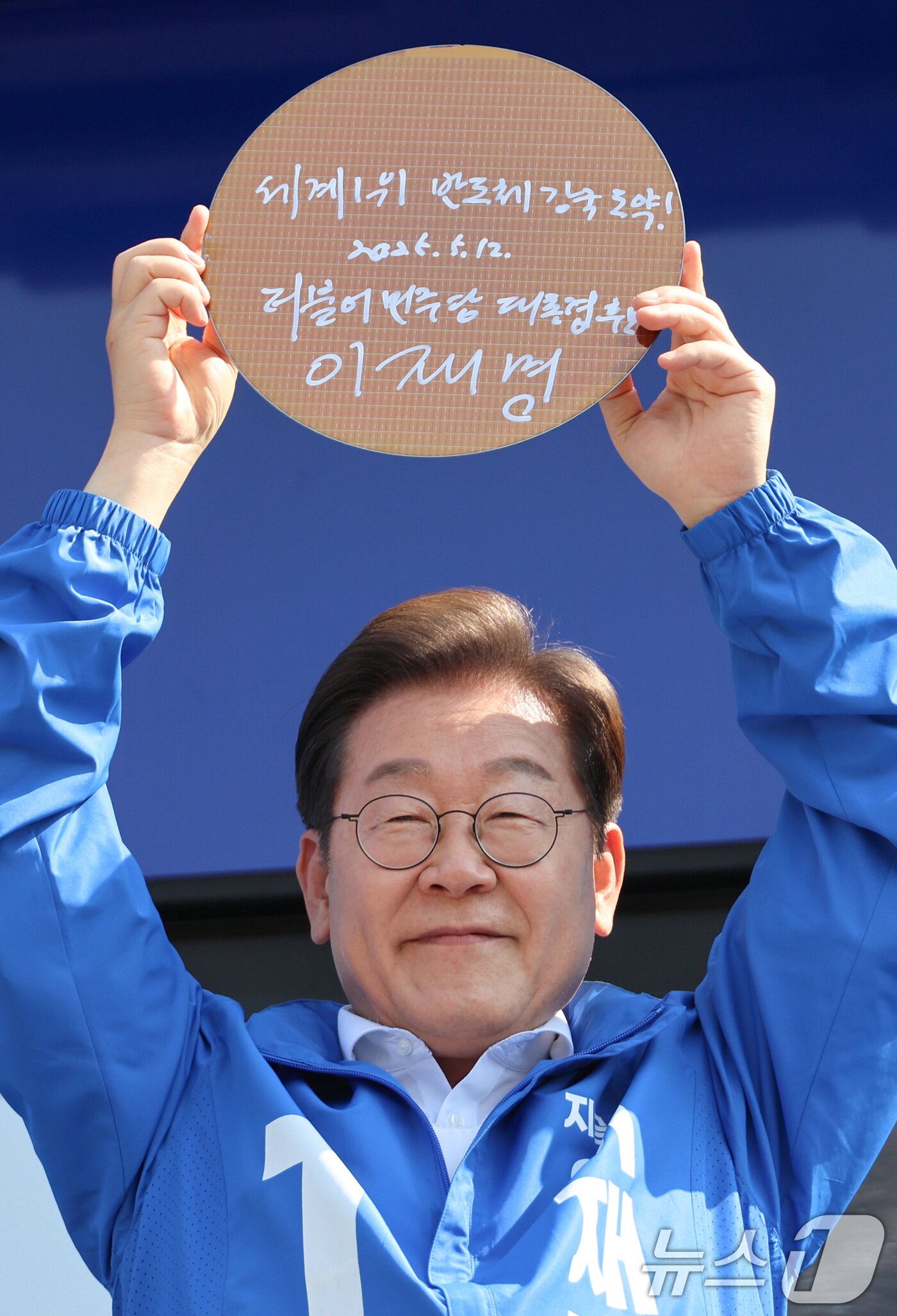 본문 이미지 - 이재명 더불어민주당 대통령 후보가 제21대 대통령 선거 공식 선거운동 첫날인 12일 오후 경기 화성시 동탄 센트럴파크 음악분수중앙광장에서 &#39;세계1위! 반도체 강국도약!&#39;이라고 쓴 반도체 웨이퍼를 들어 보이고 있다. &#40;공동취재&#41; 2025.5.12/뉴스1 ⓒ News1 안은나 기자