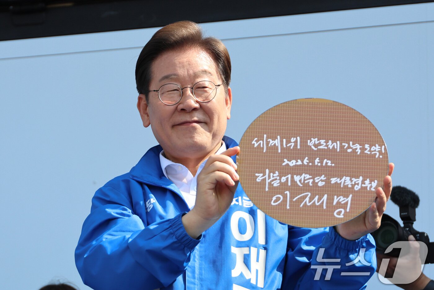 본문 이미지 - 이재명 더불어민주당 대통령 후보가 제21대 대통령 선거 공식 선거운동 첫날인 12일 오후 경기 화성시 동탄 센트럴파크 음악분수중앙광장에서 &#39;세계1위! 반도체 강국도약!&#39;이라고 쓴 반도체 웨이퍼를 들어 보이고 있다. &#40;공동취재&#41; 2025.5.12/뉴스1 ⓒ News1 안은나 기자