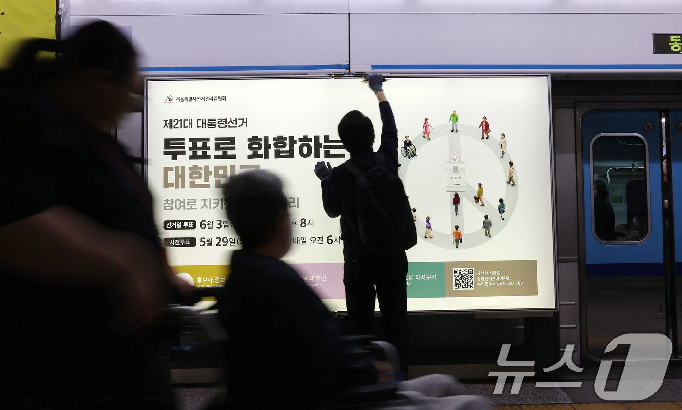 본문 이미지 - 제21대 대통령선거를 20일 앞둔 14일 오전 서울 종로구 지하철 혜화역 승강장 스크린도어에 선관위 관계자들이 대선 홍보물 래핑작업을 하고 있다. 2025.5.14/뉴스1 ⓒ News1 박세연 기자