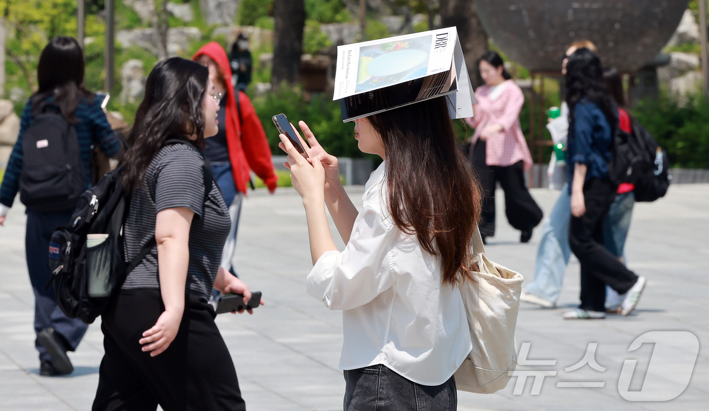 (서울=뉴스1) 김진환 기자 = 서울 낮 최고 기온이 25도를 기록하며 초여름 날씨를 보인 14일 오후 서울 서대문구 대현동 이화여자대학교에서 한 여학생이 책으로 머리를 가린 채 …
