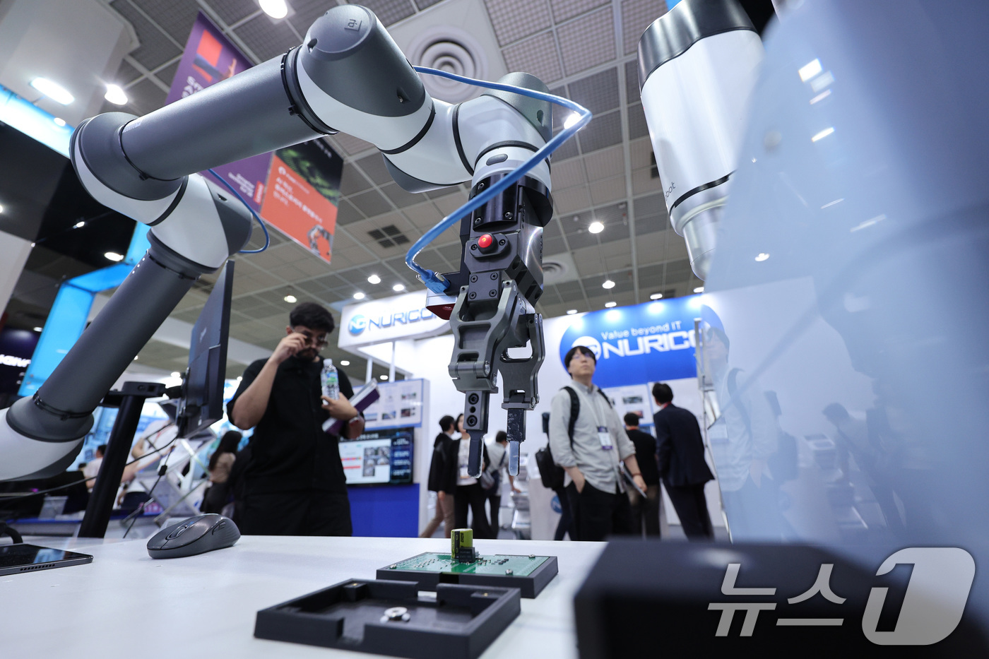 (서울=뉴스1) 신웅수 기자 = 14일 서울 강남구 코엑스에서 열린 국제인공지능대전에서 관람객들이 인공지능(AI)을 활용한 로봇팔을 살펴보고 있다. 2025.5.14/뉴스1