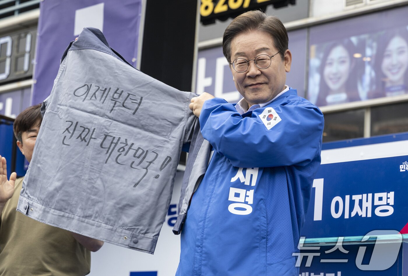 본문 이미지 - 더불어민주당 이재명 대통령 후보가 14일 오후 경남 창원시 성산구 상남분수 광장에서 한 지지자가 건넨 &#39;이제부터 진짜 대한민국!&#39;이라는 선거 문구가 적힌 옷을 바라보고 있다. &#40;공동취재&#41; 2025.5.14/뉴스1 ⓒ News1 안은나 기자