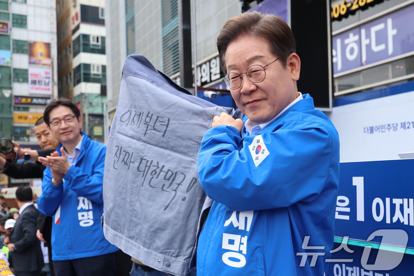 본문 이미지 - 이재명 더불어민주당 대통령 후보가 민주당 험지로 꼽히는 부산·경남&#40;PK&#41; 지역 유세에 나선 14일 경남 창원시 상남분수광장에서 열린 집중유세에서 송순호 경남도당위원장으로부터 &#39;이제부터 진짜 대한민국!&#39; 문구가 써진 작업복을 전달 받고 있다. &#40;공동취재&#41; 2025.5.14/뉴스1 ⓒ News1 안은나 기자