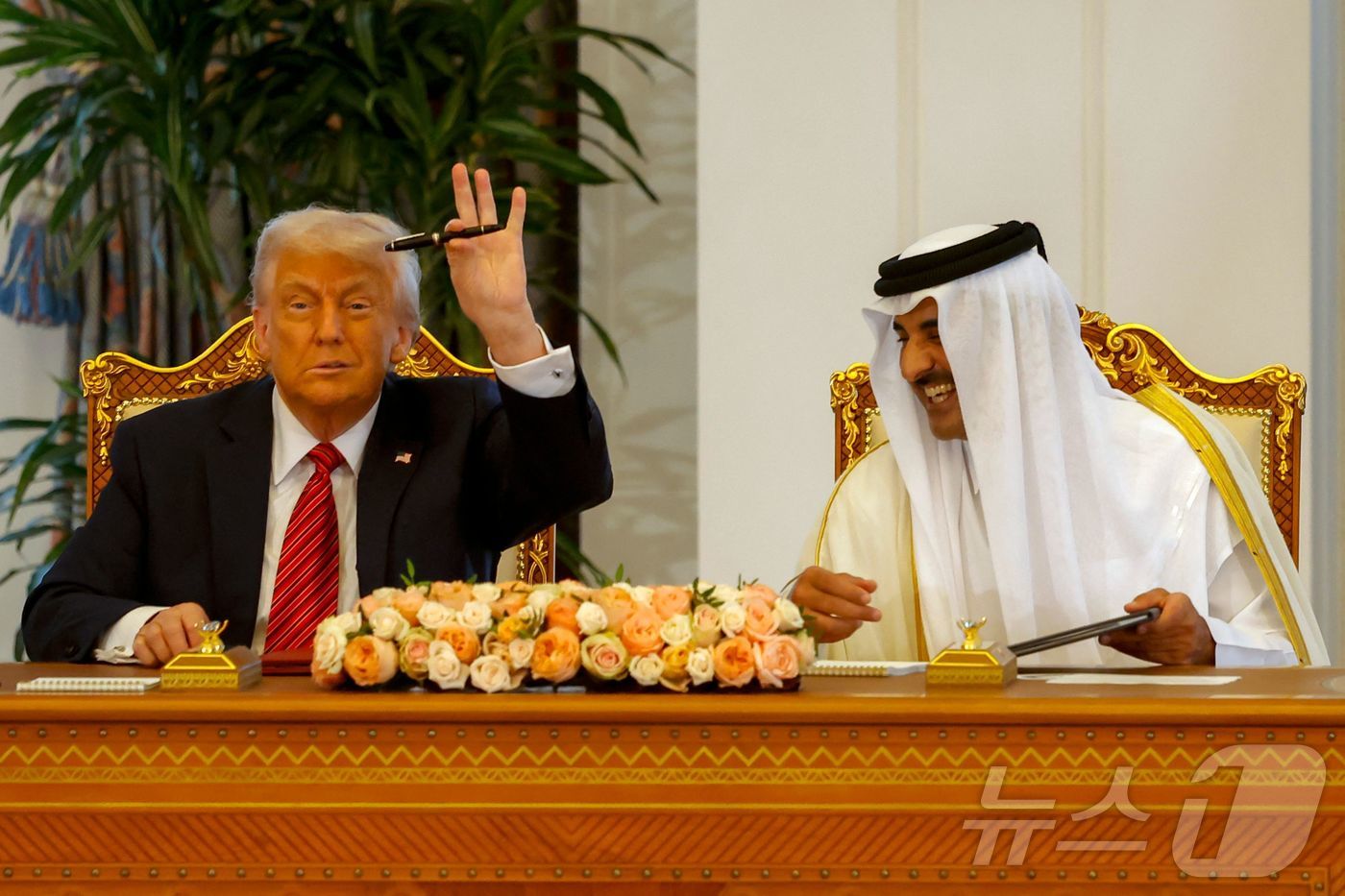 (도하 AFP=뉴스1) 우동명 기자 = 도널드 트럼프 미국 대통령이 14일(현지시간) 중동 순방 중 도하 왕궁에서 열린 셰이크 타밈 빈 하마드 알사니 카타르 국왕과 서명식서 펜을 …