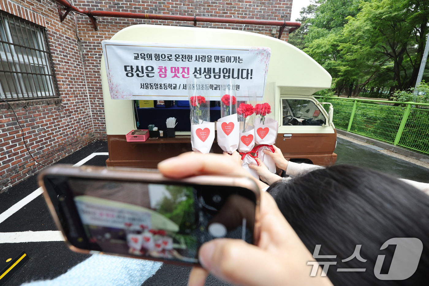 (서울=뉴스1) 신웅수 기자 = 스승의 날인 15일 오전 서울 노원구 동일초등학교에 마련된 커피차 앞에서 선생님들이 선물받은 꽃을 들고 기념 촬영하고 있다. 2025.5.15/뉴스 …