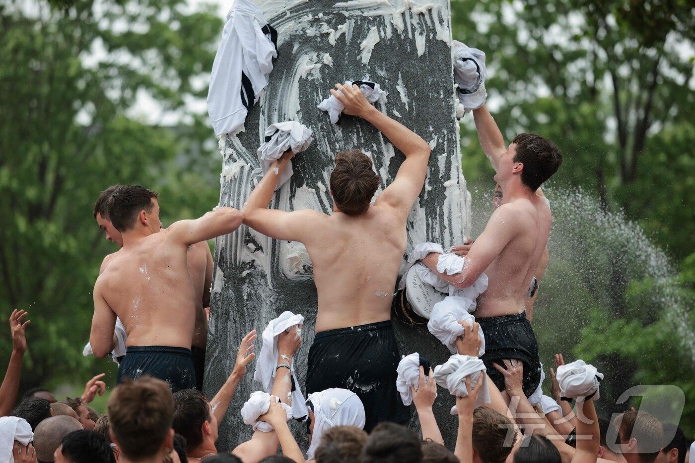 본문 이미지 - 미국 해군사관학교에서 사관생도들이 14일(현지시간) 미국 메릴랜드 주 아나폴리스 미 해군 사관학교에서 '딕시 컵'을 떨어뜨리기 위해 인간 피라미드를 만들어 헌던 기념물 꼭대기에 오르고 있다.  ⓒ AFP=뉴스1