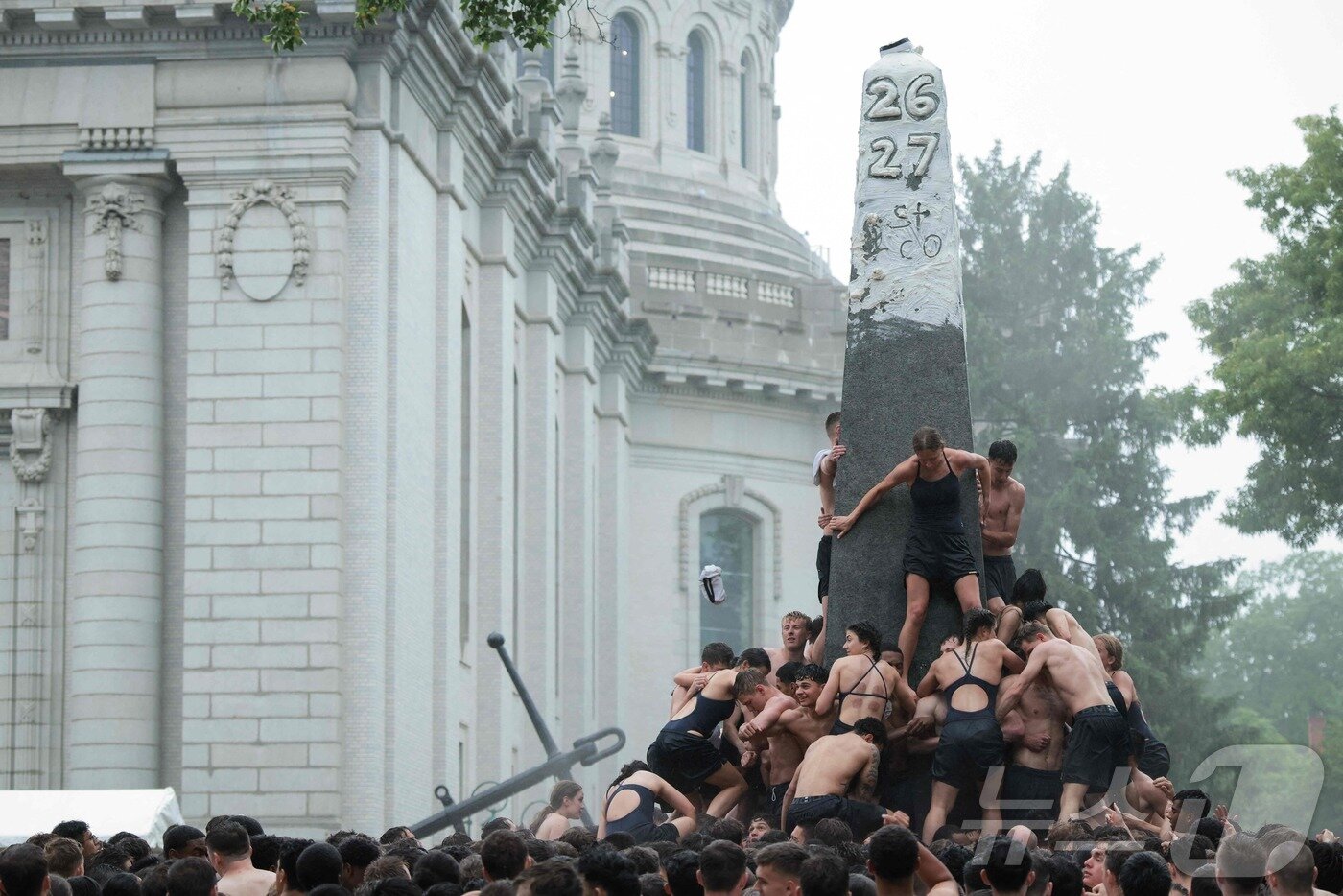 본문 이미지 - 미국 해군사관학교에서 사관생도들이 14일(현지시간) 미국 메릴랜드 주 아나폴리스 미 해군 사관학교에서 '딕시 컵'을 떨어뜨리기 위해 인간 피라미드를 만들어 헌던 기념물 꼭대기에 오르고 있다. ⓒ AFP=뉴스1