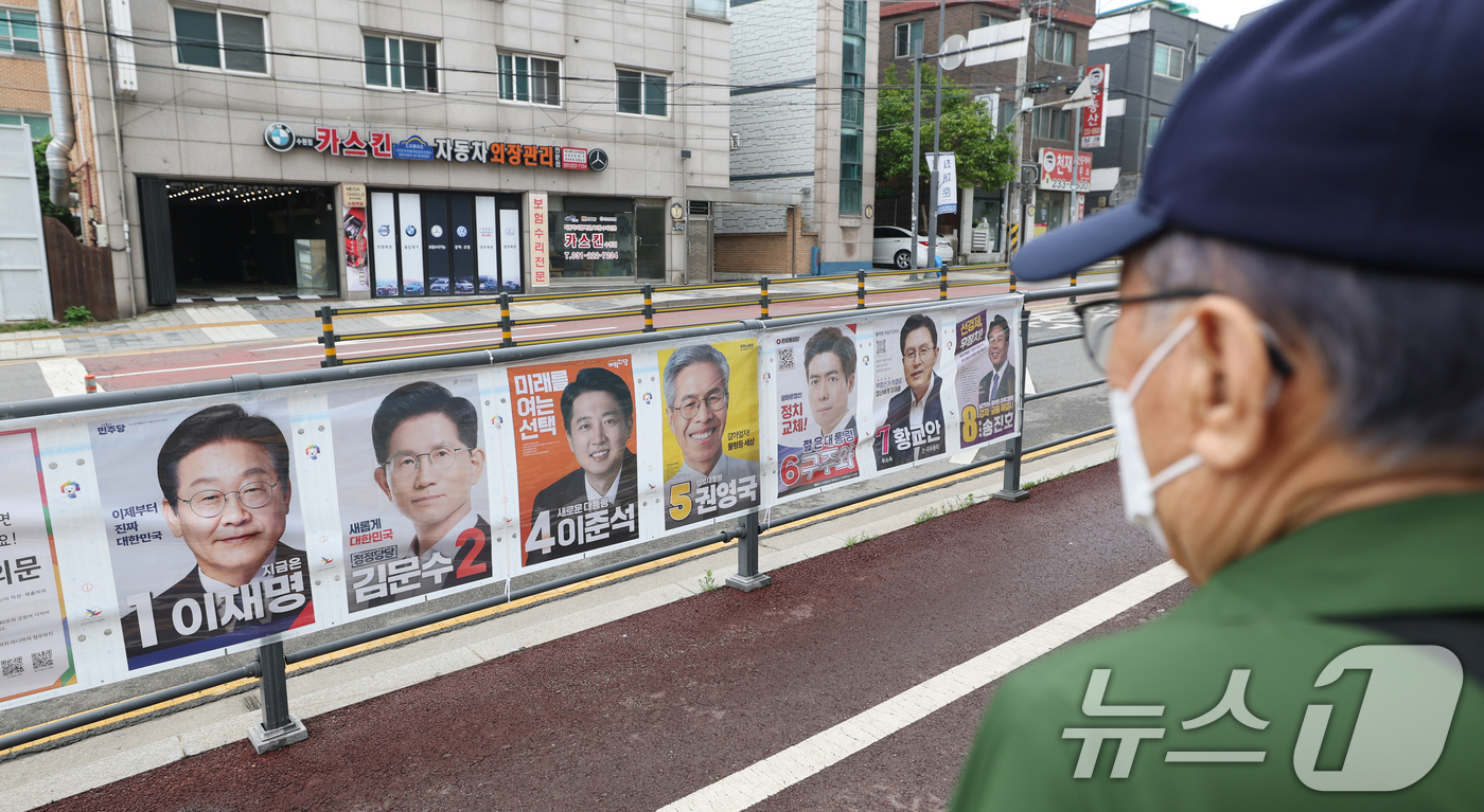 (수원=뉴스1) 김영운 기자 = 15일 경기 수원시 권선구의 한 거리에서 시민들이 제21대 대통령선거 후보자들 선거 벽보를 보고 있다. 2025.5.15/뉴스1