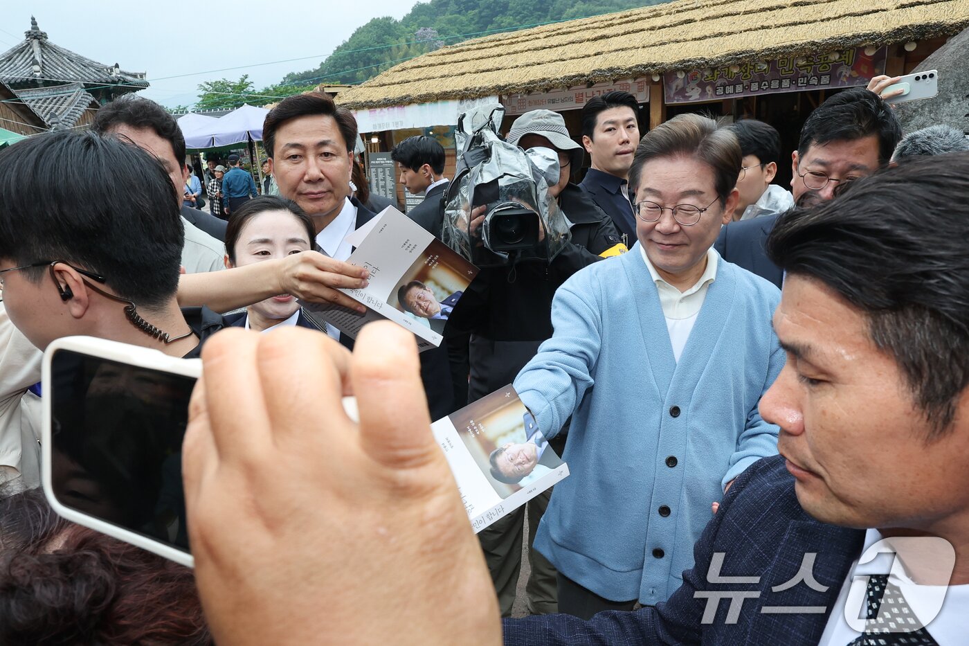 본문 이미지 - 이재명 더불어민주당 대통령 후보가 15일 오전 경남 하동군 화개장터 입구에서 유튜브 K-이니셔TV 케미폭발 &#39;동서화합&#39; 화개장터 라이브 오프닝을 마치고 이동하던 중 지지자들에게 사인해주고 있다. 2025.5.15/뉴스1 ⓒ News1 안은나 기자