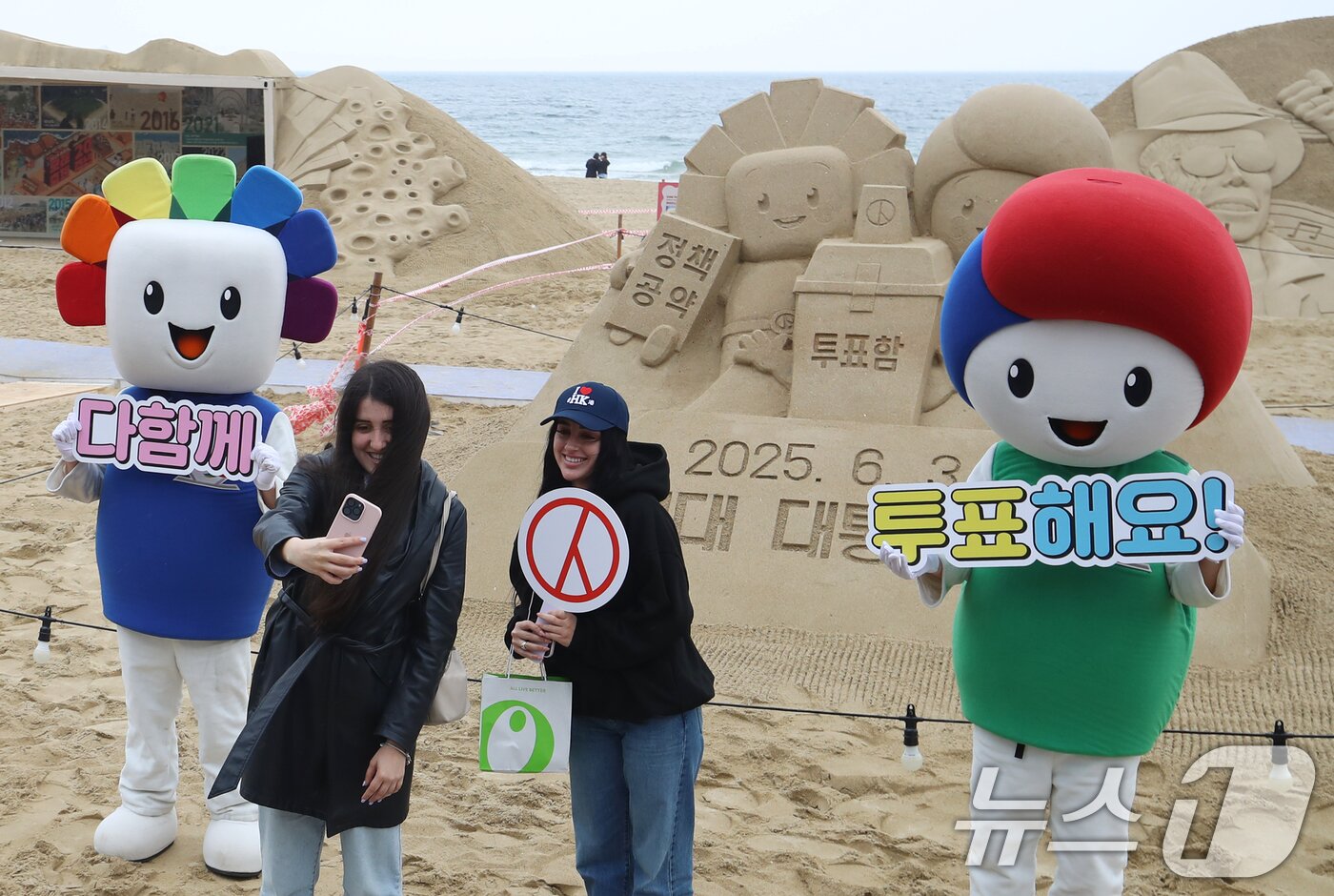 본문 이미지 - 제21대 대통령선거를 앞둔 15일 오후 부산 해운대해수욕장에서 정책·공약에 대한 관심과 투표 참여를 높이기 위해 부산시선관위의 &#39;모래로 만나는 대통령선거&#39; 홍보 캠페인이 진행되는 가운데 외국인 관광객들이 모래작품 앞에서 셀카를 찍고 있다. 2025.5.15/뉴스1 ⓒ News1 윤일지 기자