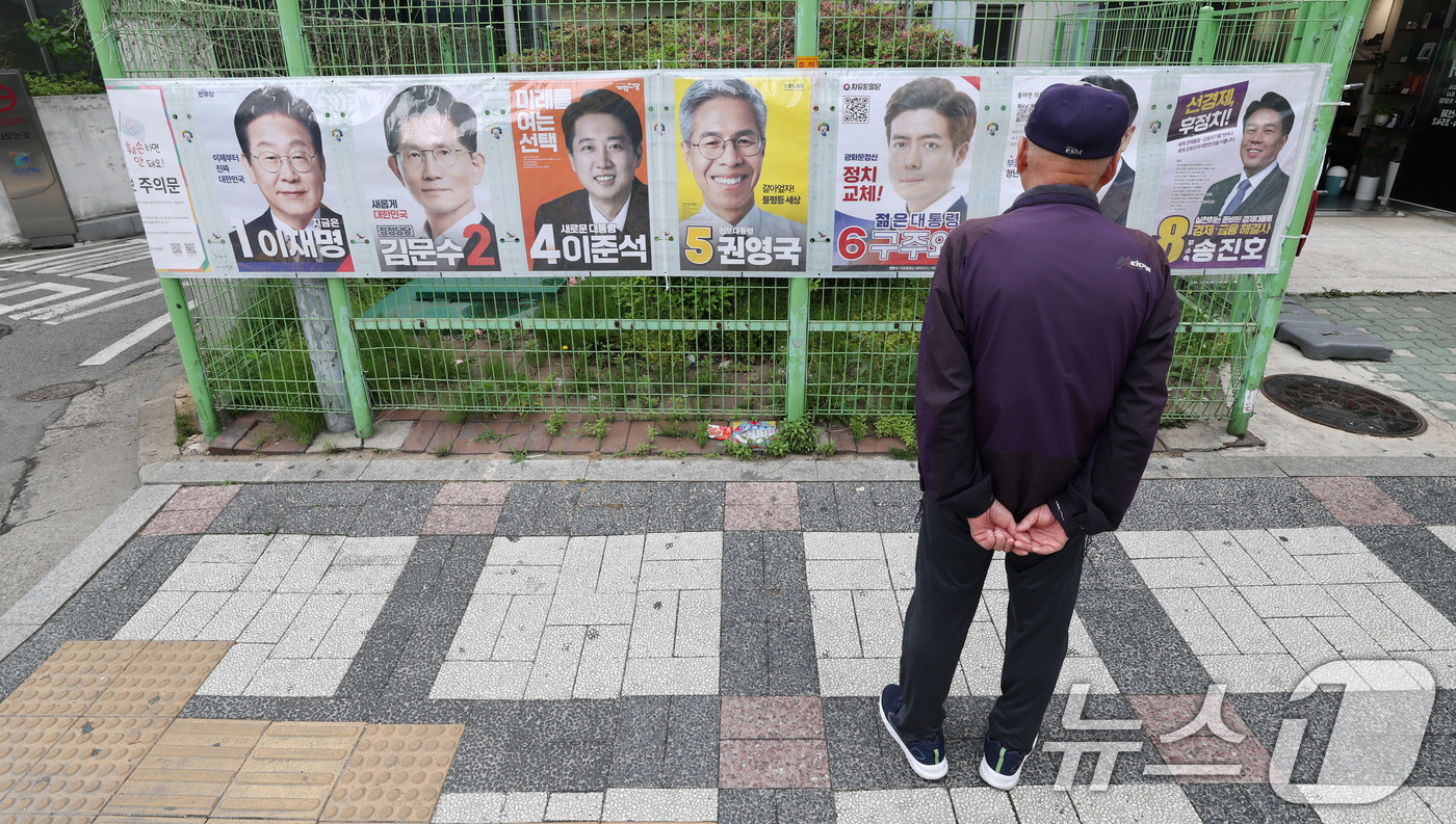 (서울=뉴스1) 박세연 기자 = 15일 한 유권자가 서울 양천구 목동2차 성원아파트 앞에 첩부된 제21대 대통령선거 후보자 벽보를 살펴보고 있다.선거벽보는 이날부터 전국 8만290 …