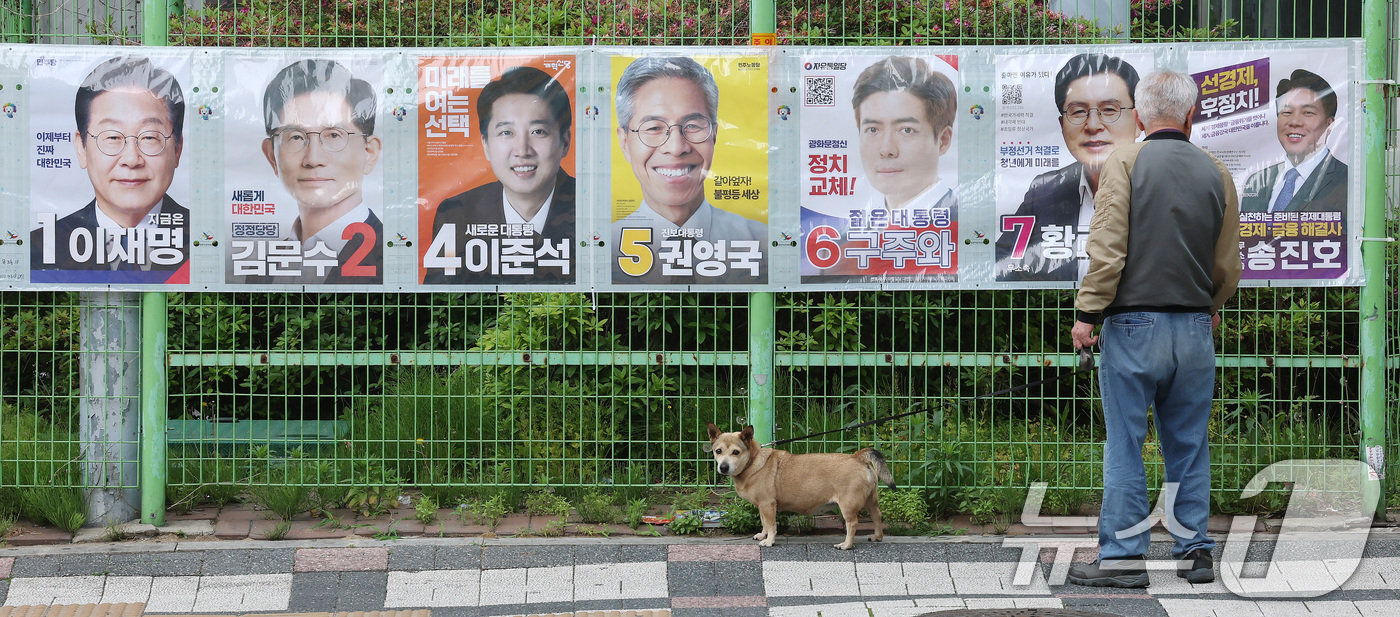 (서울=뉴스1) 박세연 기자 = 15일 반려견과 산책을 나온 한 유권자가 서울 양천구 목동2차 성원아파트 앞에 부착된 제21대 대통령선거 후보자 벽보를 살펴보고 있다.선거벽보는 이 …