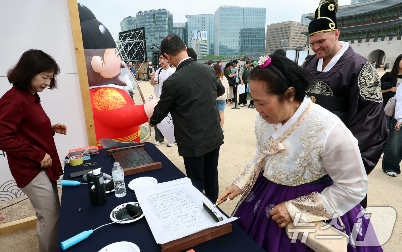 (서울=뉴스1) 김명섭 기자 = 15일 경복궁 흥례문 앞 광장에서 ‘628돌 세종대왕 나신 날 기념행사’에서 외국인 관광객들이 훈민정음 서문 탁본 체험을 하고 있다.‘세종대왕 나신 …