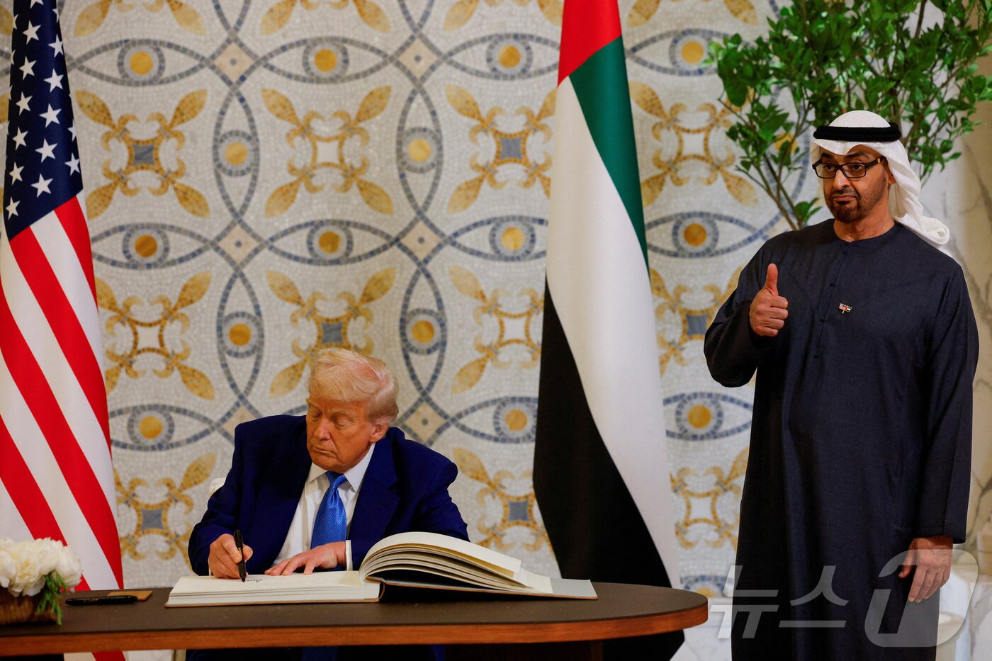 본문 이미지 - 도널드 트럼프 미국 대통령이 15일&#40;현지시간&#41; 아부다비의 대통령 궁에서 방명록에 서명을 하는 동안 셰이크 무함마드 빈 자이드 알 나흐얀 UAE 대통령이 엄지를 치켜 세우고 있다. 2025.05.16 ⓒ 로이터=뉴스1 ⓒ News1 우동명 기자