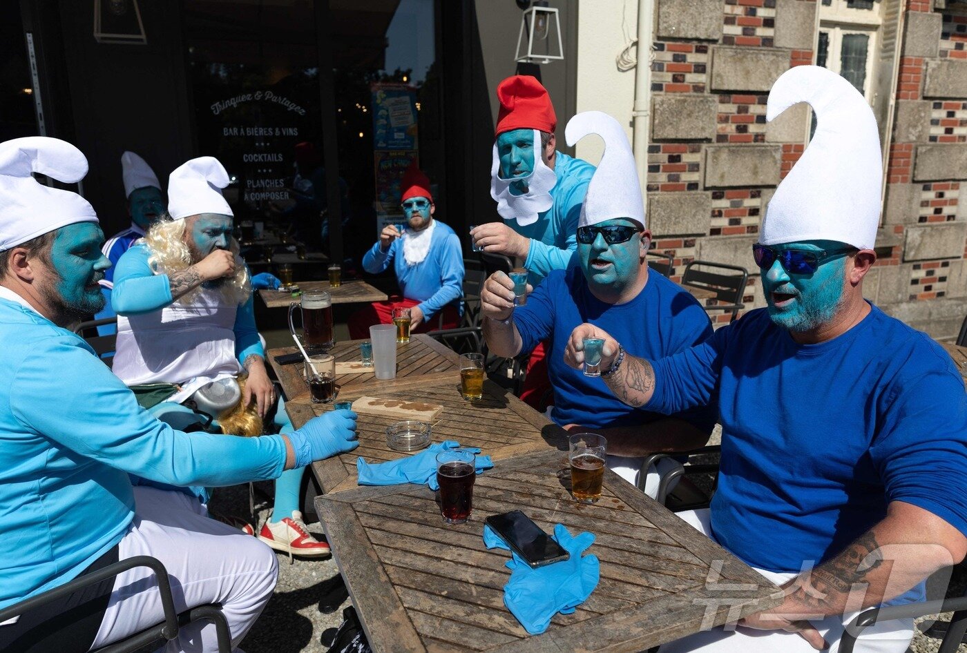 본문 이미지 - 프랑스 서부 랑데르노의 한 카페 테라스에서 17일(현지시간) 스머프 복장을 한 스머프 세계 도전 참가자들이 파란색 술이 담긴 잔을 들고 있다. ⓒ AFP=뉴스1 ⓒ News1 권영미 기자