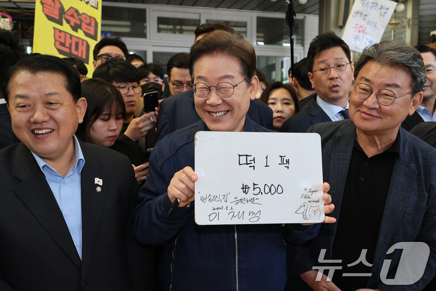 (철원=뉴스1) 이재명 기자 = '골목골목 경청투어 : 접경벨트편'에 나선 이재명 더불어민주당 대통령 후보가 2일 오전 강원 철원군 동송전통시장에 위치한 떡집에 들러 가격판에 서명 …