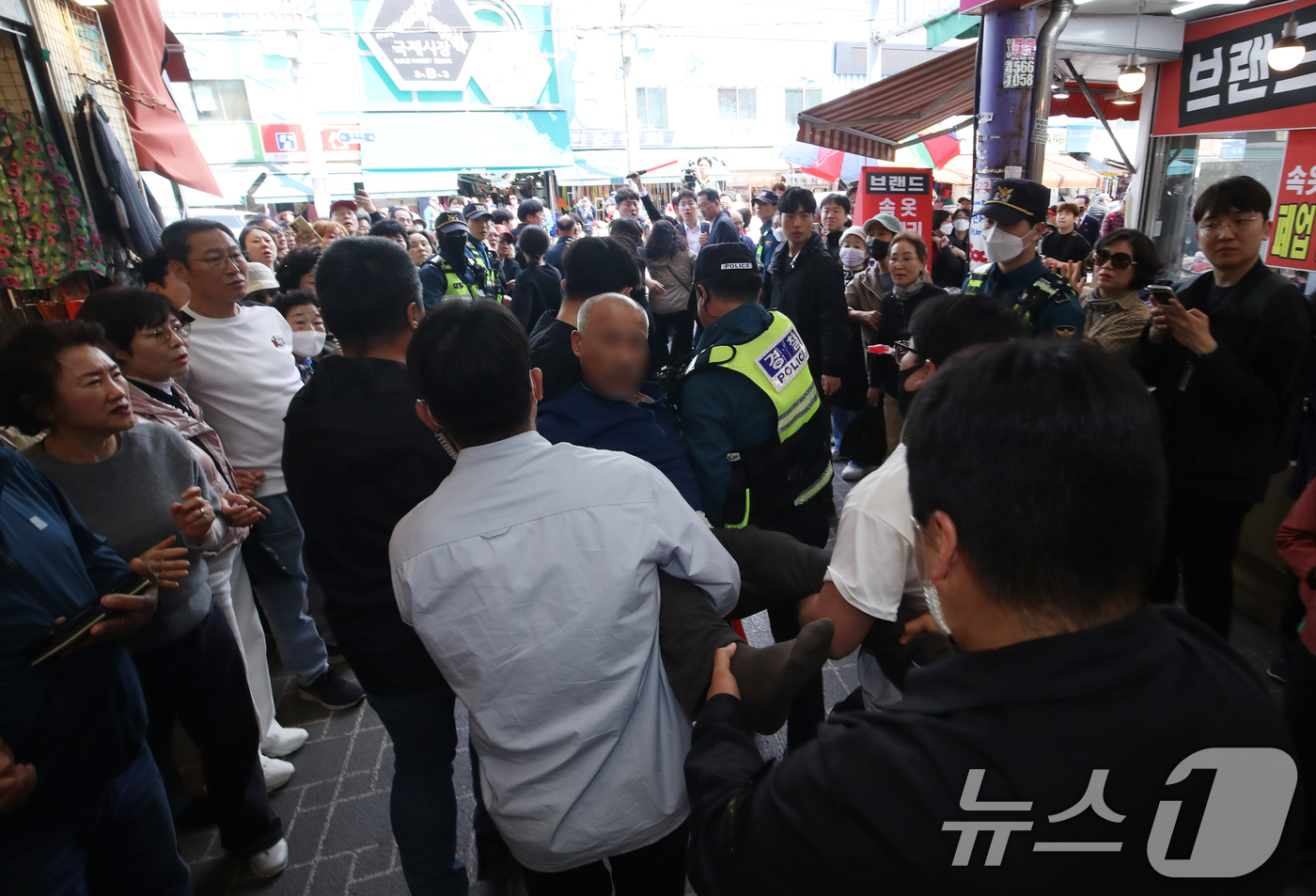 (부산=뉴스1) 윤일지 기자 = 2일 오후 부산 중구 부평깡통시장을 방문한 한동훈 국민의힘 대선 경선 후보를 욕설과 함께 비난한 한 시민이 경찰에 제지되고 있다. 2025.5.2/ …