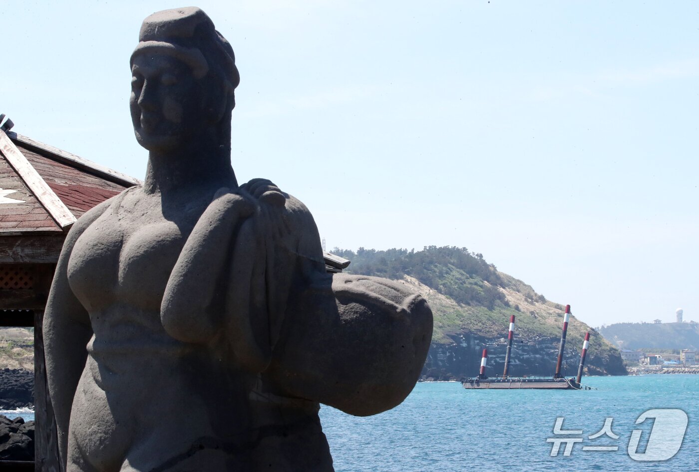 본문 이미지 - 제주 해녀상 뒤로 보이는 좌초된 &#39;페리지에어로스페이스&#39;의 우주발사체 해상 발사장 세테시아1.