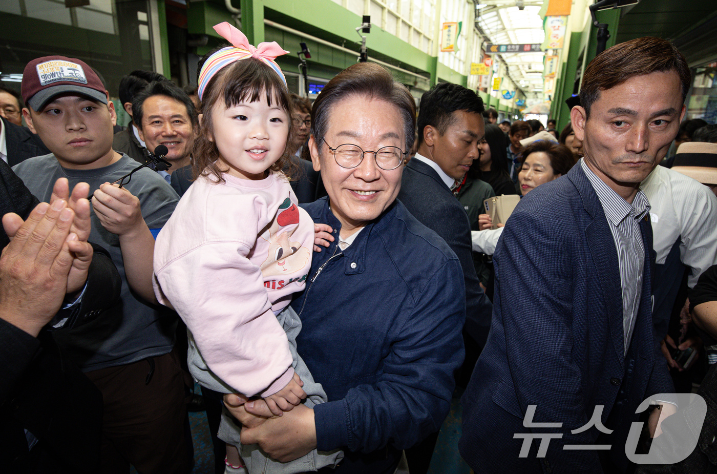 (인제=뉴스1) 이재명 기자 = '골목골목 경청투어 : 접경벨트편'에 나선 이재명 더불어민주당 대통령 후보가 2일 오후 강원 인제군 북면 원통시장에서 어린이를 안고 기념촬영을 하고 …