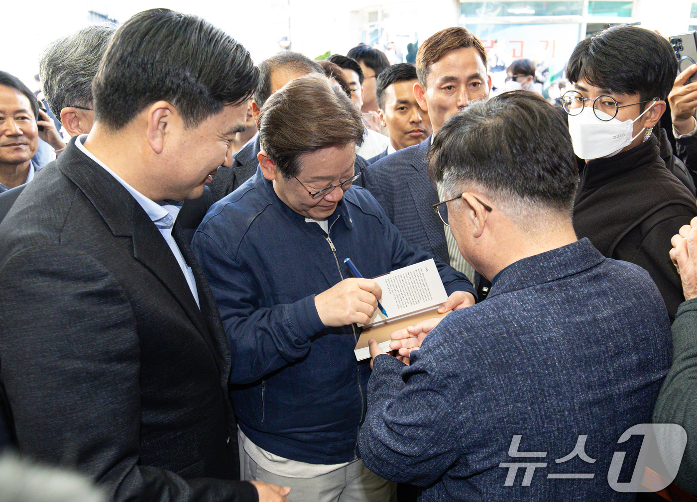 (인제=뉴스1) 이재명 기자 = '골목골목 경청투어 : 접경벨트편'에 나선 이재명 더불어민주당 대통령 후보가 2일 오후 강원 인제군 북면 원통시장에서 한 지지자 요청으로 책에 서명 …