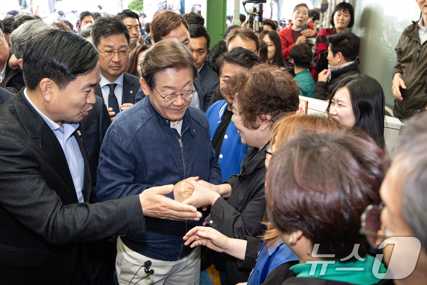 (인제=뉴스1) 이재명 기자 = '골목골목 경청투어 : 접경벨트편'에 나선 이재명 더불어민주당 대통령 후보가 2일 오후 강원 인제군 북면 원통시장에서 시민들과 인사를 나누고 있다. …