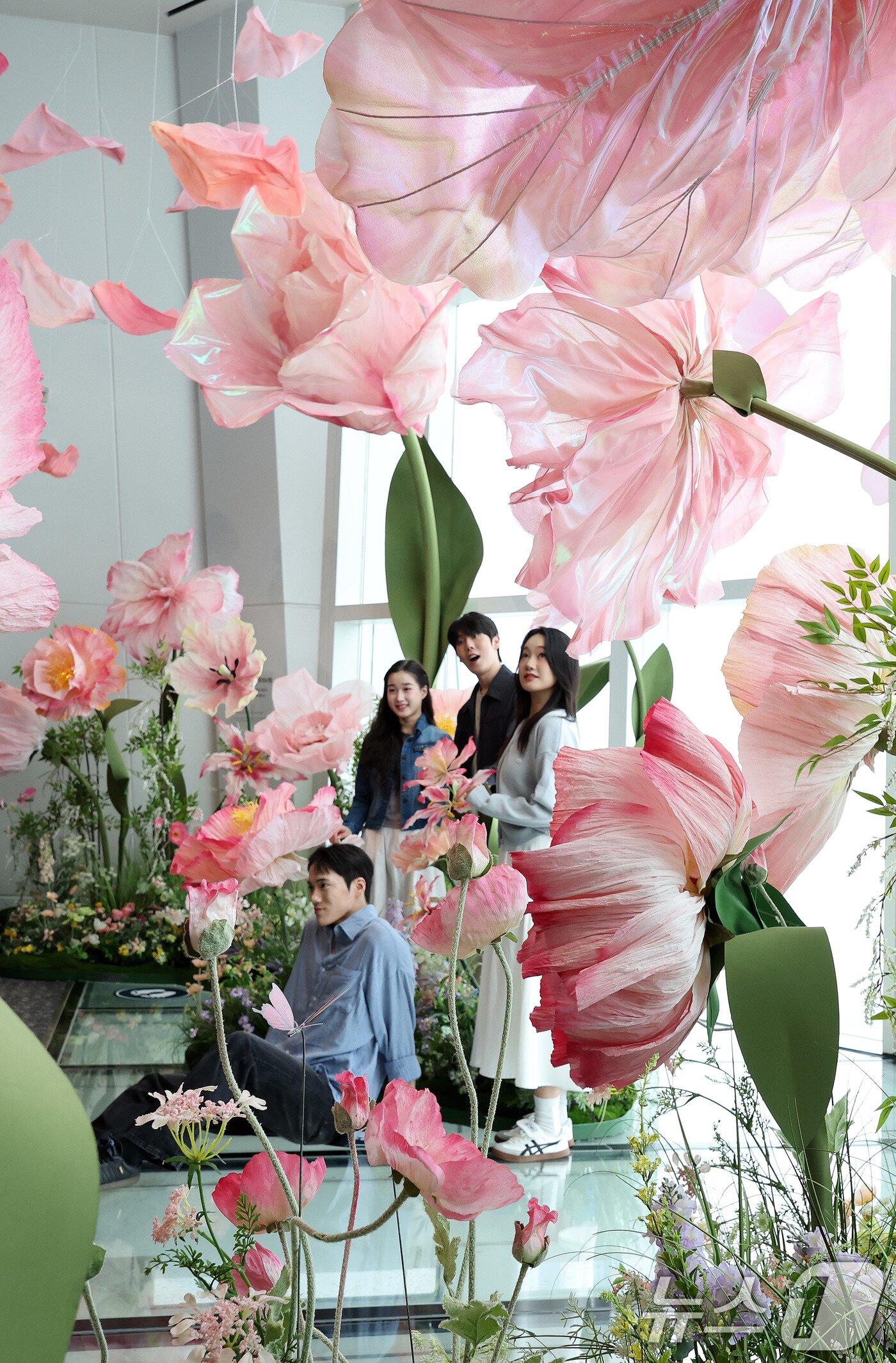 본문 이미지 - 20일 서울 송파구 롯데월드타워 전망대 서울스카이에 마련된 플라워 체험형 공간인 &#39;블루밍 유니버스: 빅플라워&#39; 앞에서 모델들이 포즈를 취하고 있다.. 2025.5.20/뉴스1 ⓒ News1 박지혜 기자