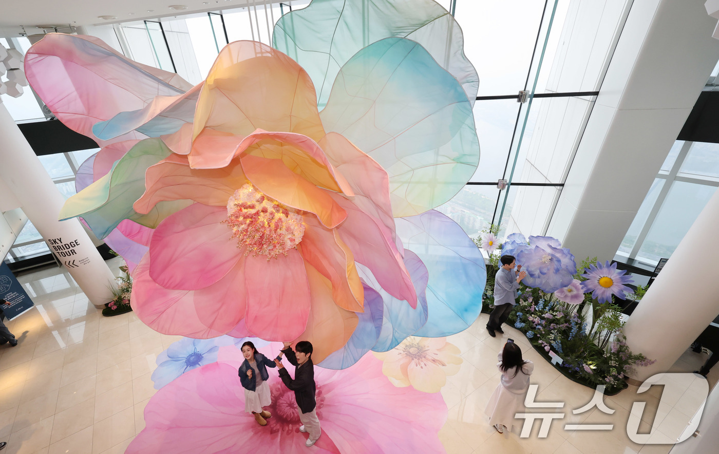 (서울=뉴스1) 박지혜 기자 = 20일 서울 송파구 롯데월드타워 전망대 서울스카이에 마련된 플라워 체험형 공간인 '블루밍 유니버스: 빅플라워' 앞에서 모델들이 포즈를 취하고 있다. …