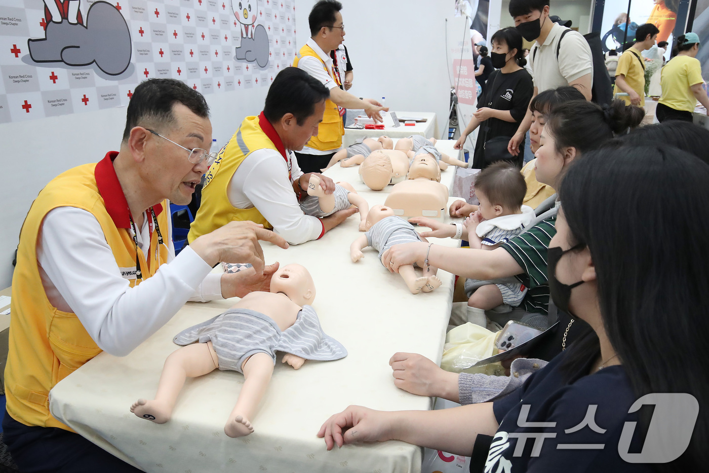 (대구=뉴스1) 공정식 기자 = 22일 대구 북구 엑스코(EXCO)에서 개막한 '2025 대구 베이비&키즈페어'를 찾은 부모들이 대한적십자사 대구지사 부스에서 영유아 응급처치법을 …