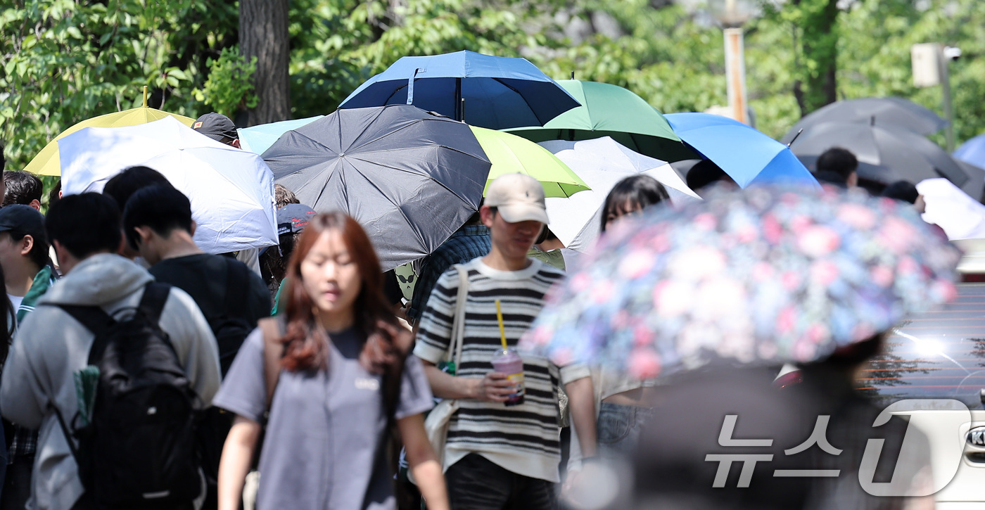(서울=뉴스1) 김성진 기자 = 전국적으로 초여름 날씨를 보인 22일 서울 광진구 건국대학교에서 학생들이 우산과 양산으로 햇빛을 가린 채 노천극장 입장을 기다리고 있다. 2025. …
